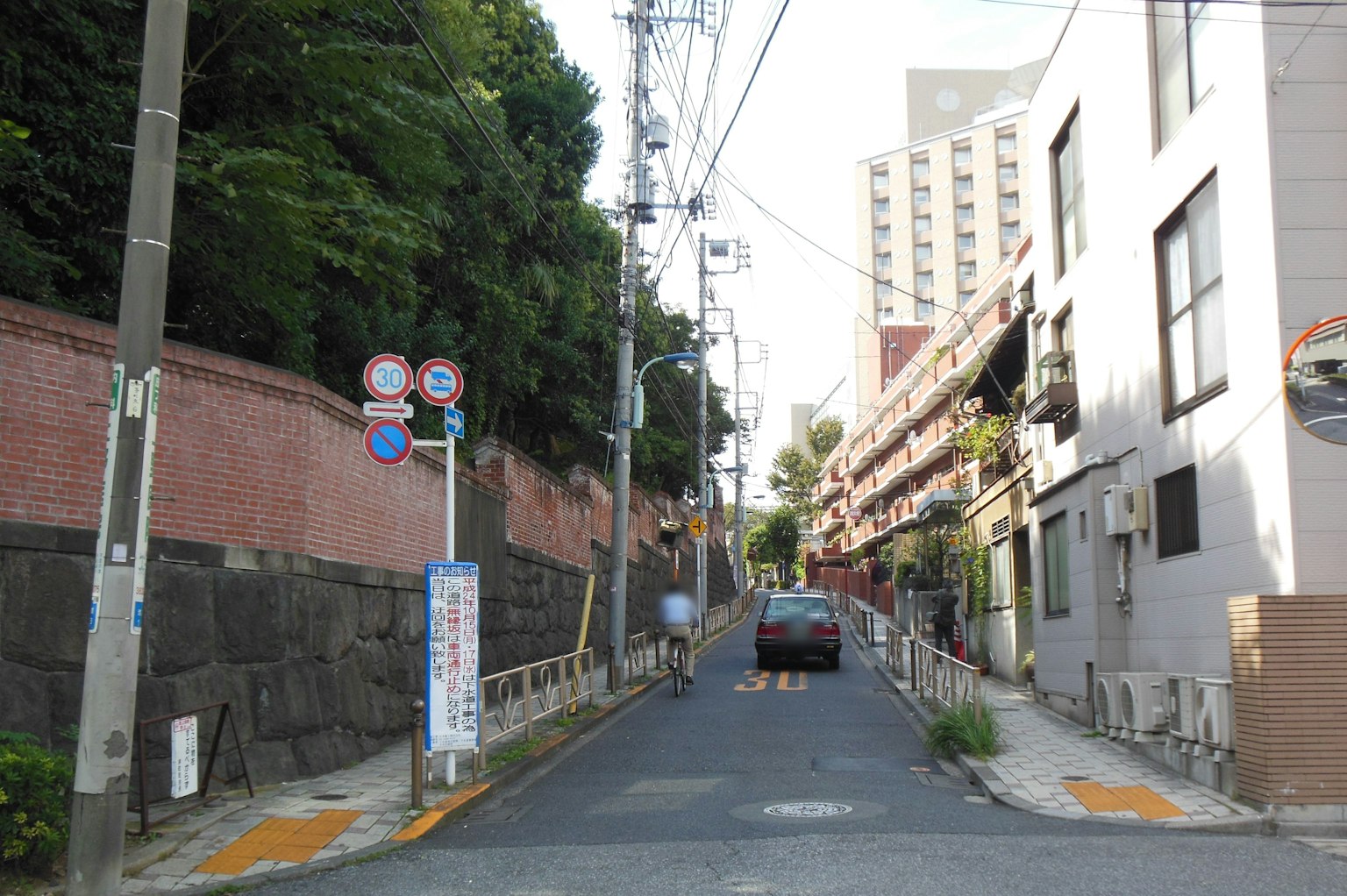 Narrow street with a red brick wall and buildings lining the sides