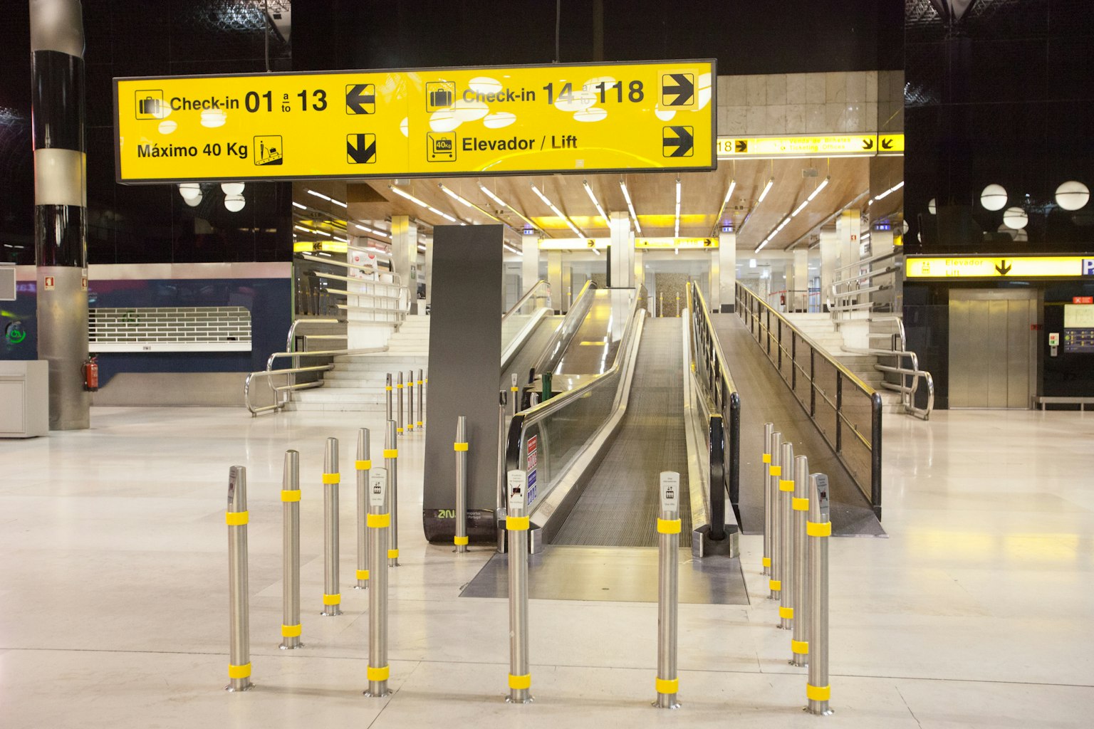 Airport interior moving area featuring escalators and yellow signage