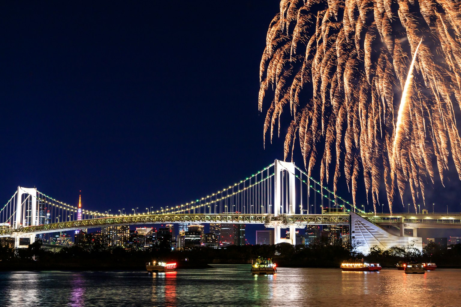 Beautiful view of Tokyo Bay featuring Rainbow Bridge and fireworks in the night sky