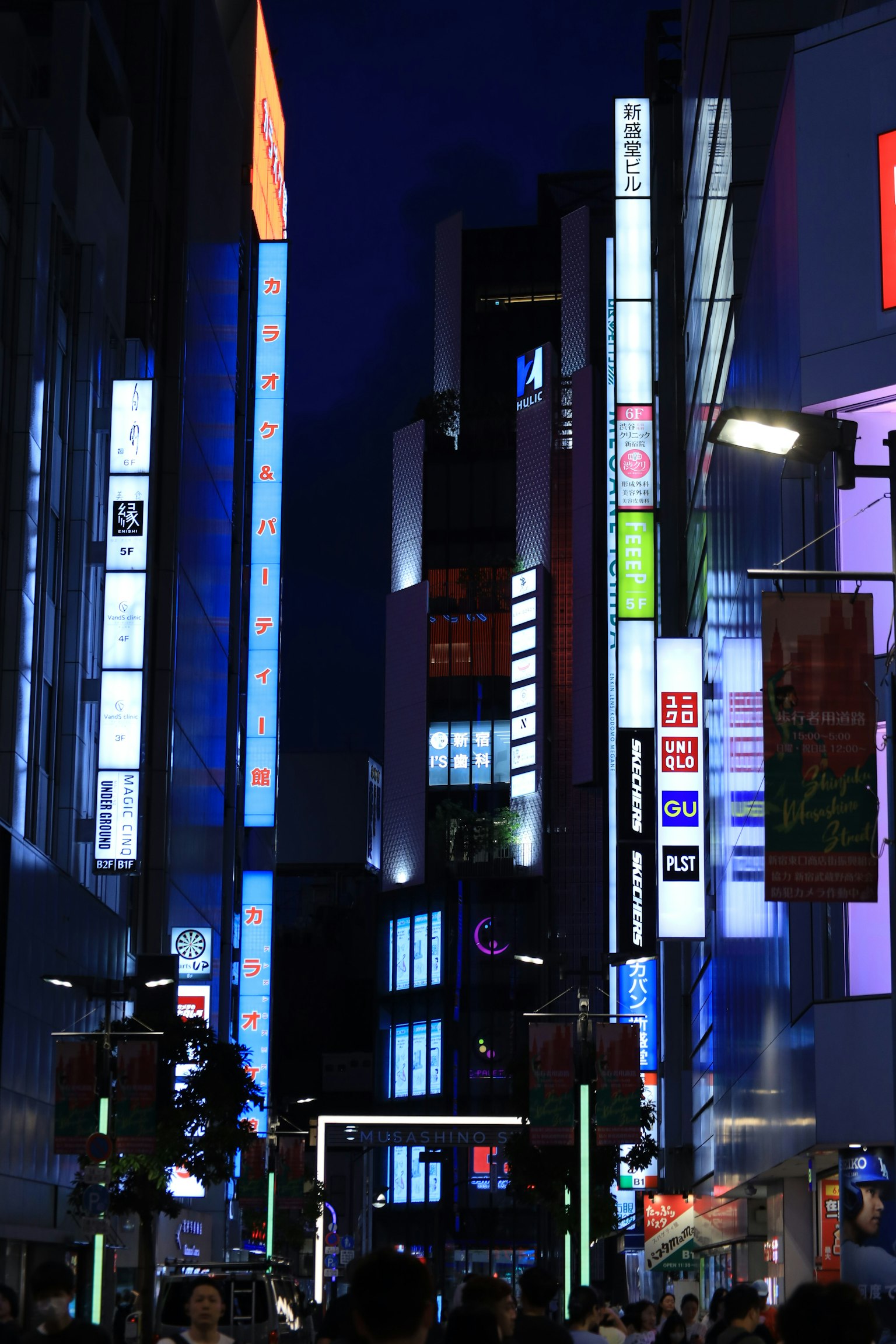 Belebte Stadtstraße bei Nacht mit Neonlichtern und Menschenmengen