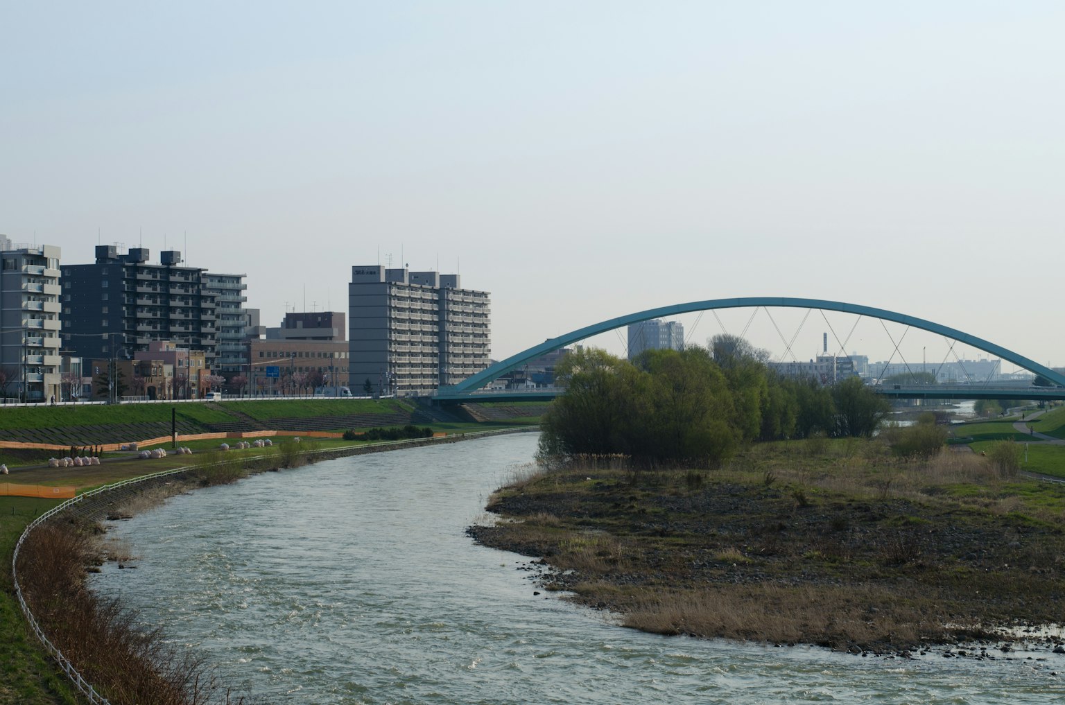 Blue arch bridge over a river with nearby buildings