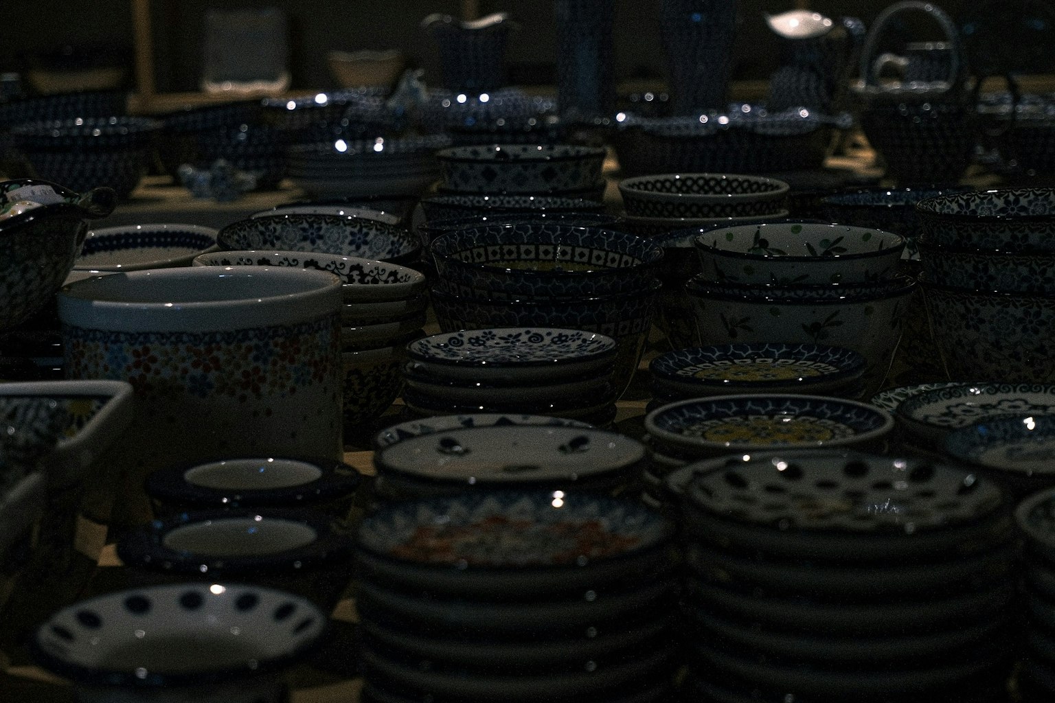 Une variété d'assiettes en céramique avec des motifs complexes disposées dans un cadre faiblement éclairé
