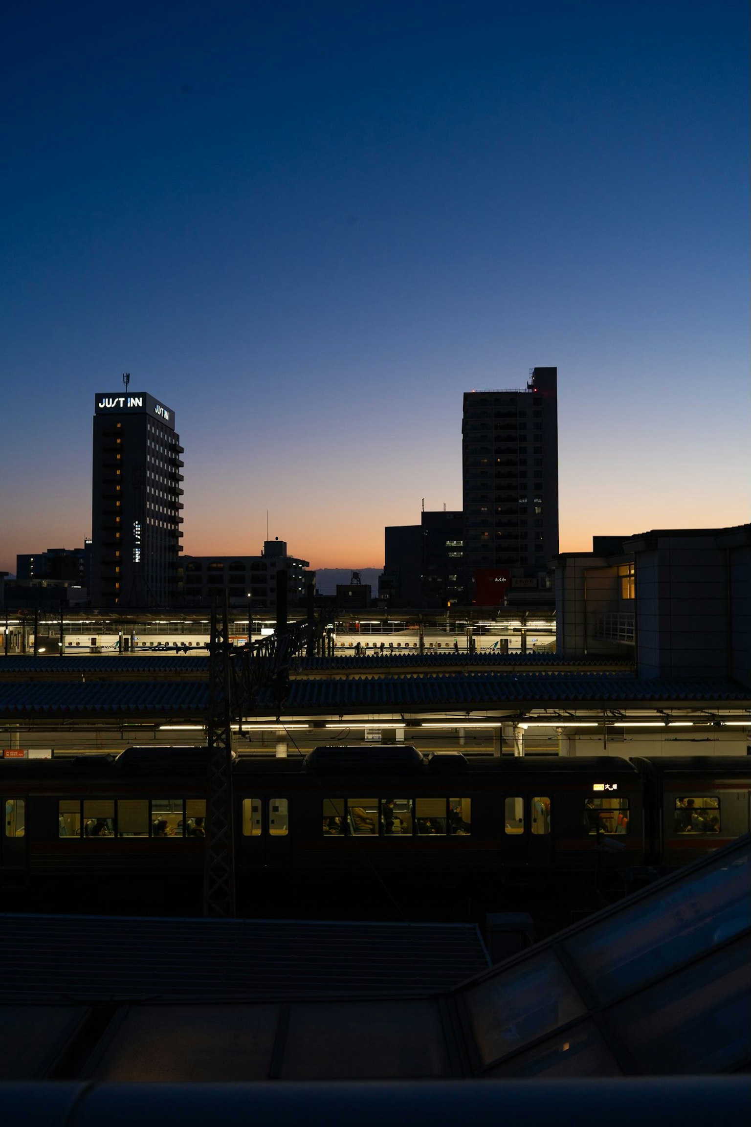 Urban skyline at dusk featuring a train station and high-rise buildings