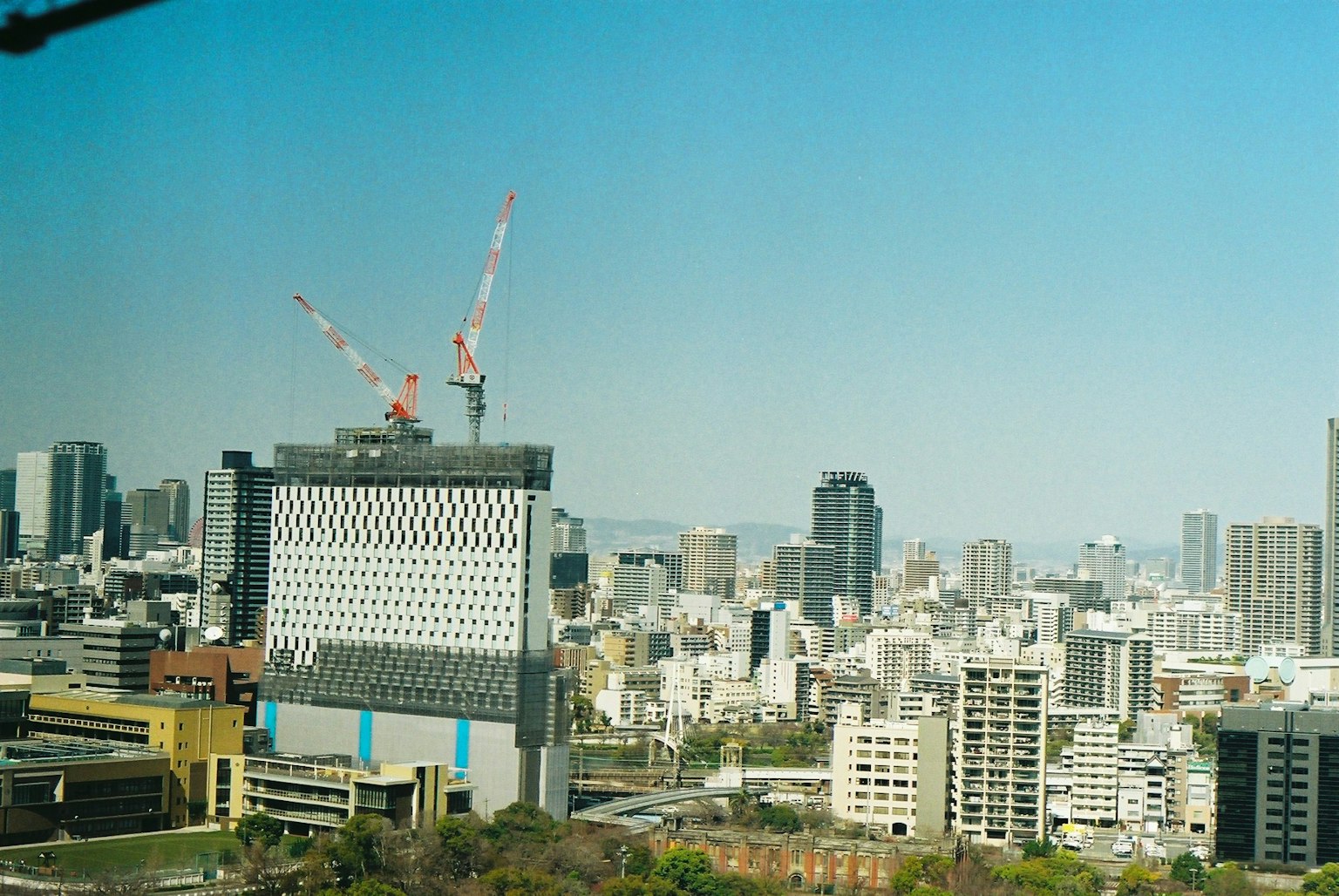 Paisaje urbano bajo un cielo azul con grúas de construcción y edificios
