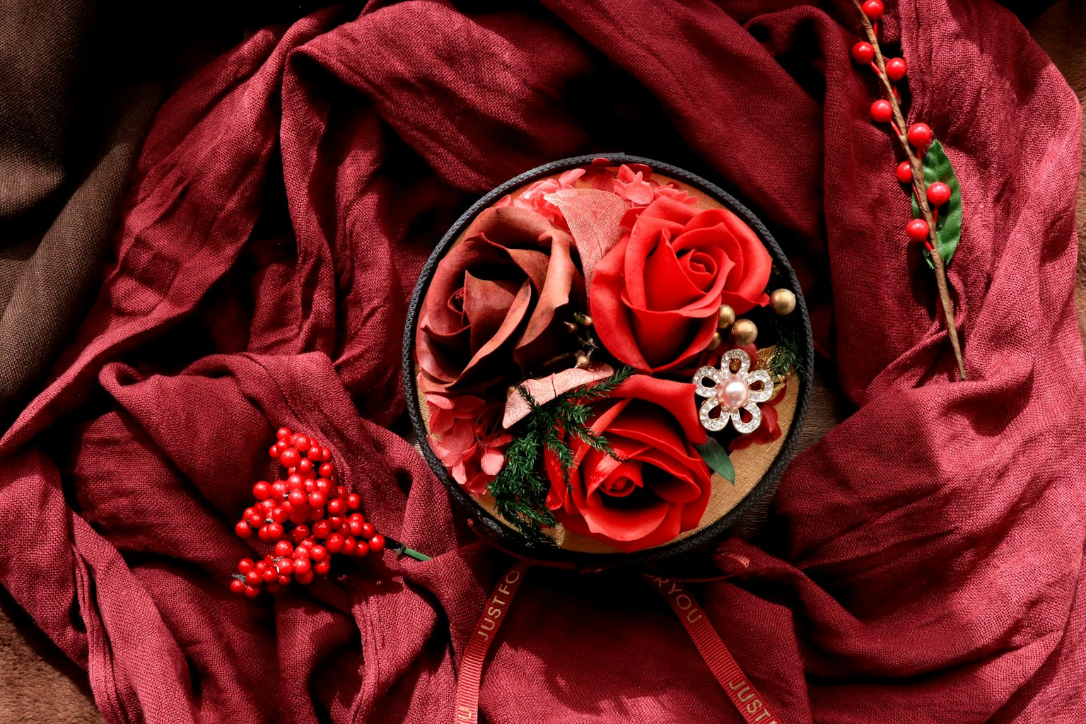 Composizione floreale con rose rosse e rosa su uno sfondo di tessuto bordeaux