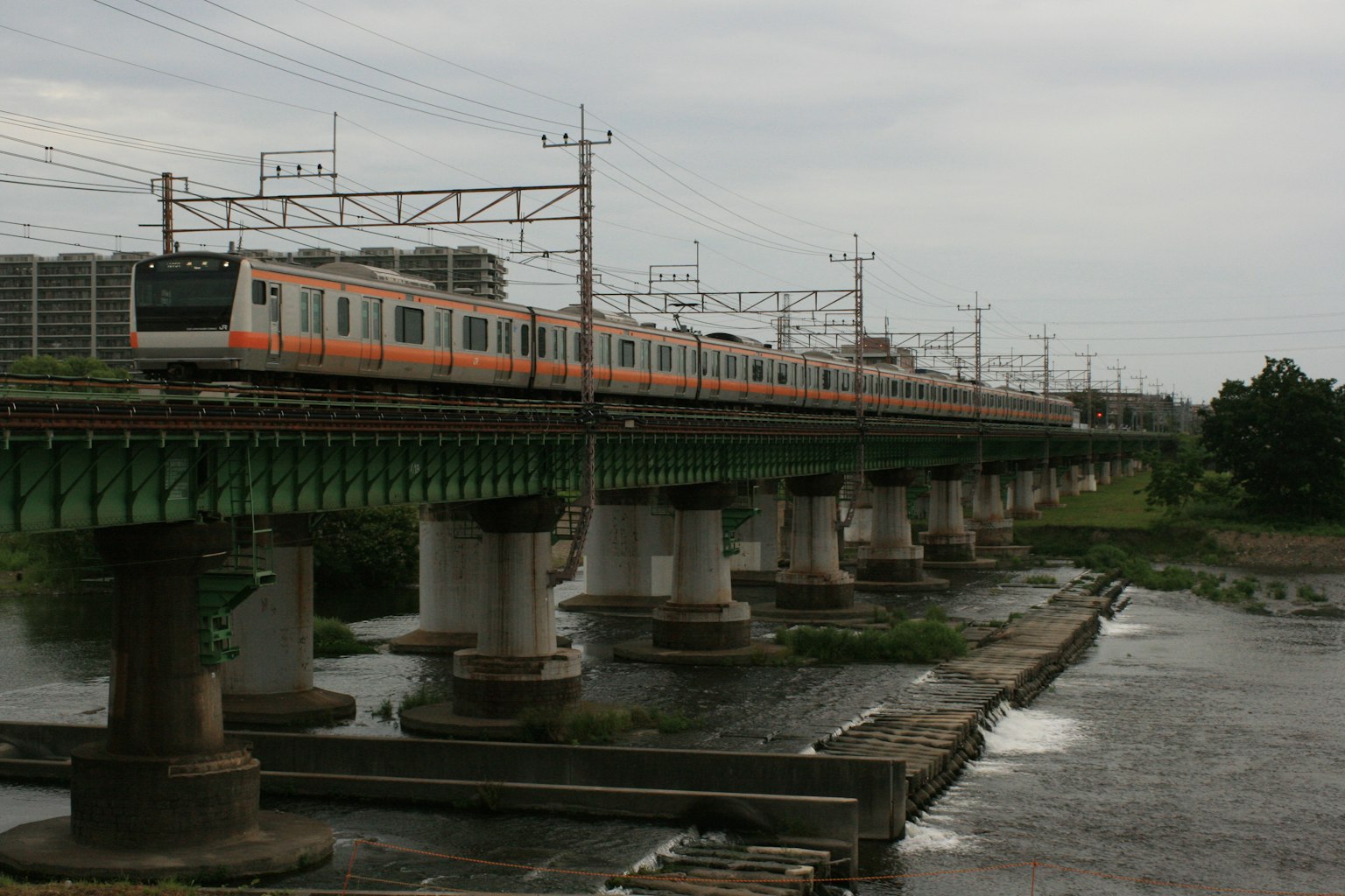 Train orange traversant un pont au-dessus d'une rivière