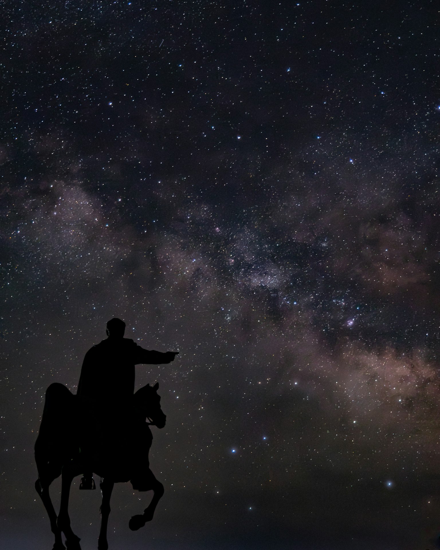 Silueta de una estatua de caballero contra un cielo estrellado y la Vía Láctea