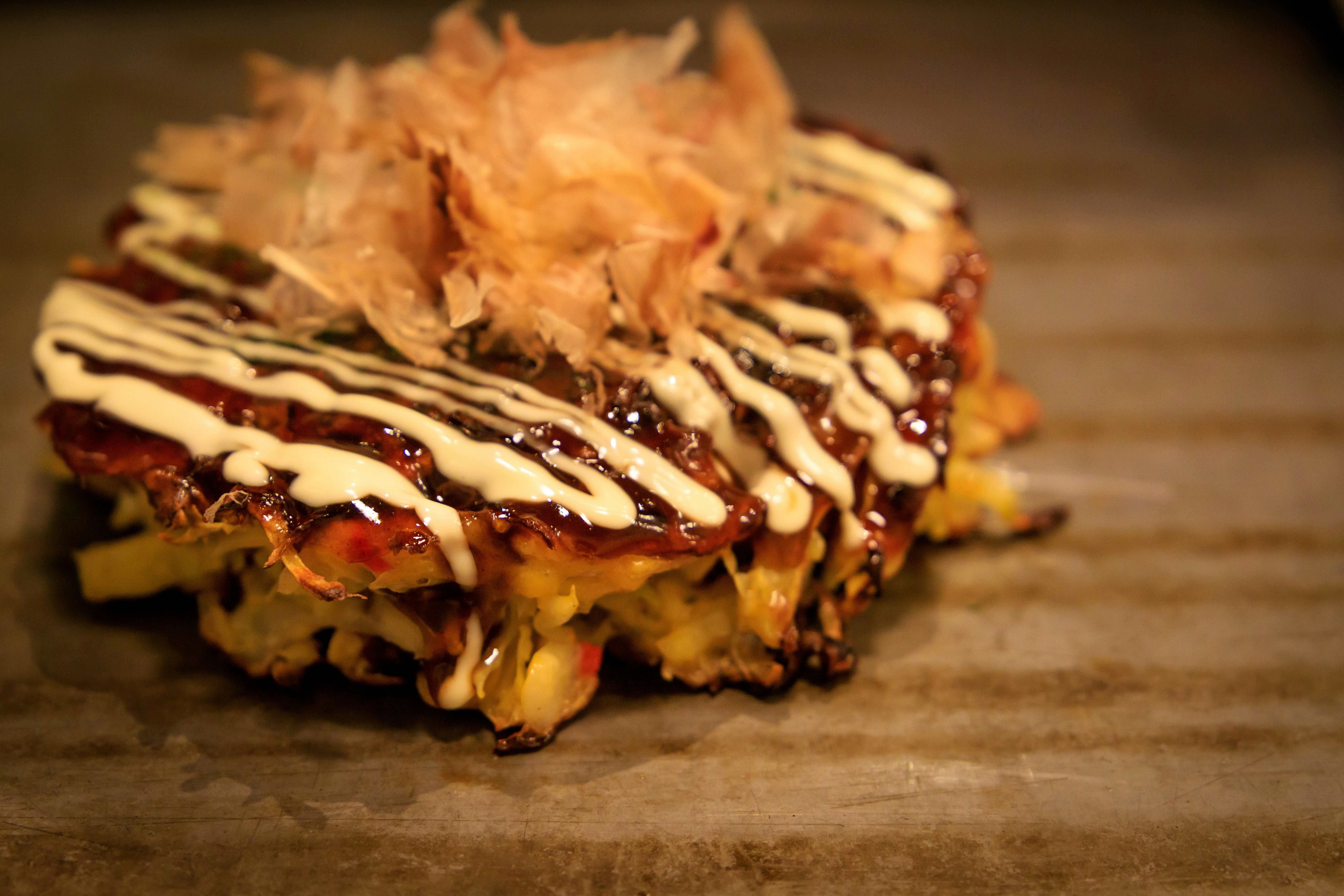お好み焼き風の焼き物にマヨネーズとソースがかかった鉄板の一皿