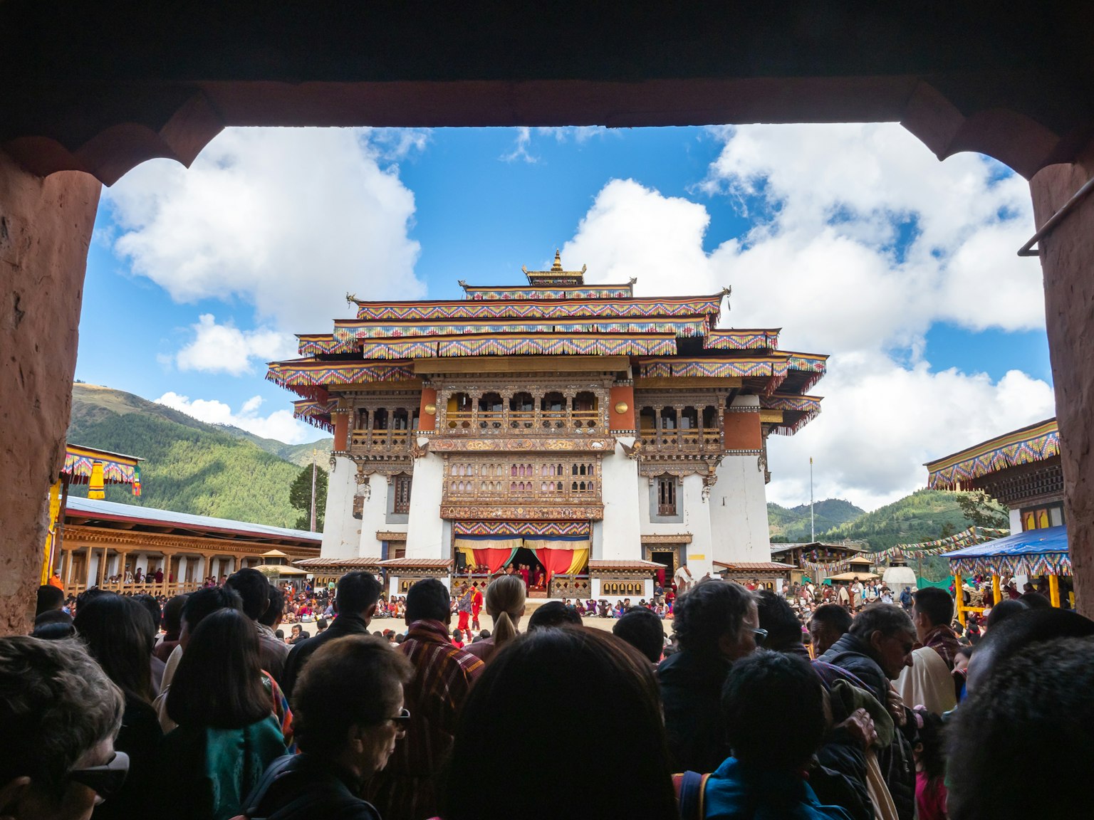 Folla radunata davanti a un tempio tradizionale bhutanese con un cielo blu splendido