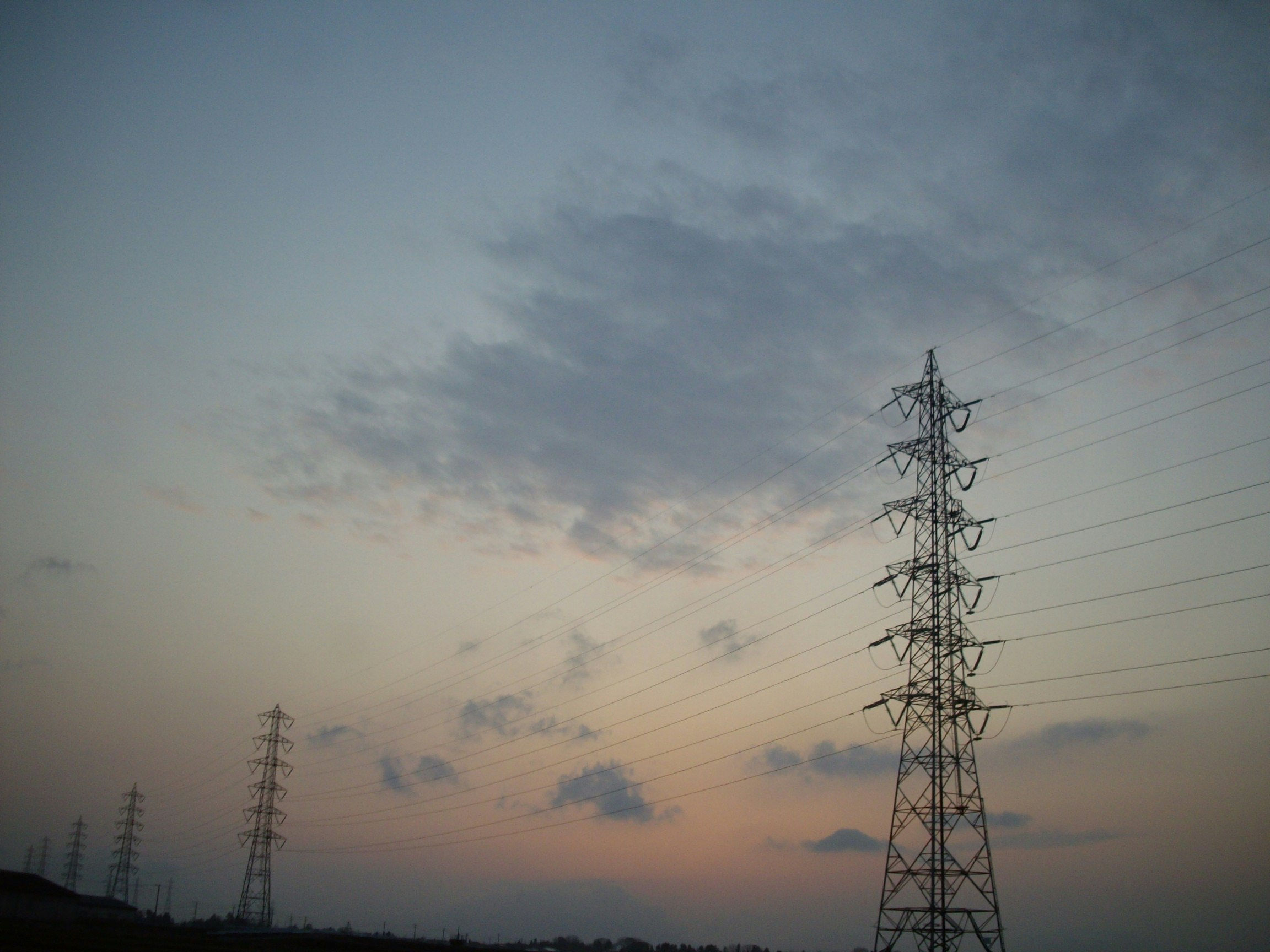 暮色中高聳的輸電鐵塔與架空電線