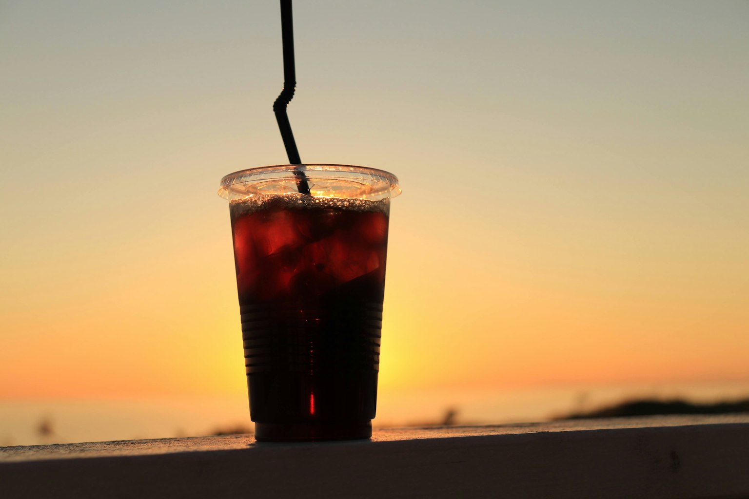 Un bicchiere di bevanda in silhouette contro un tramonto