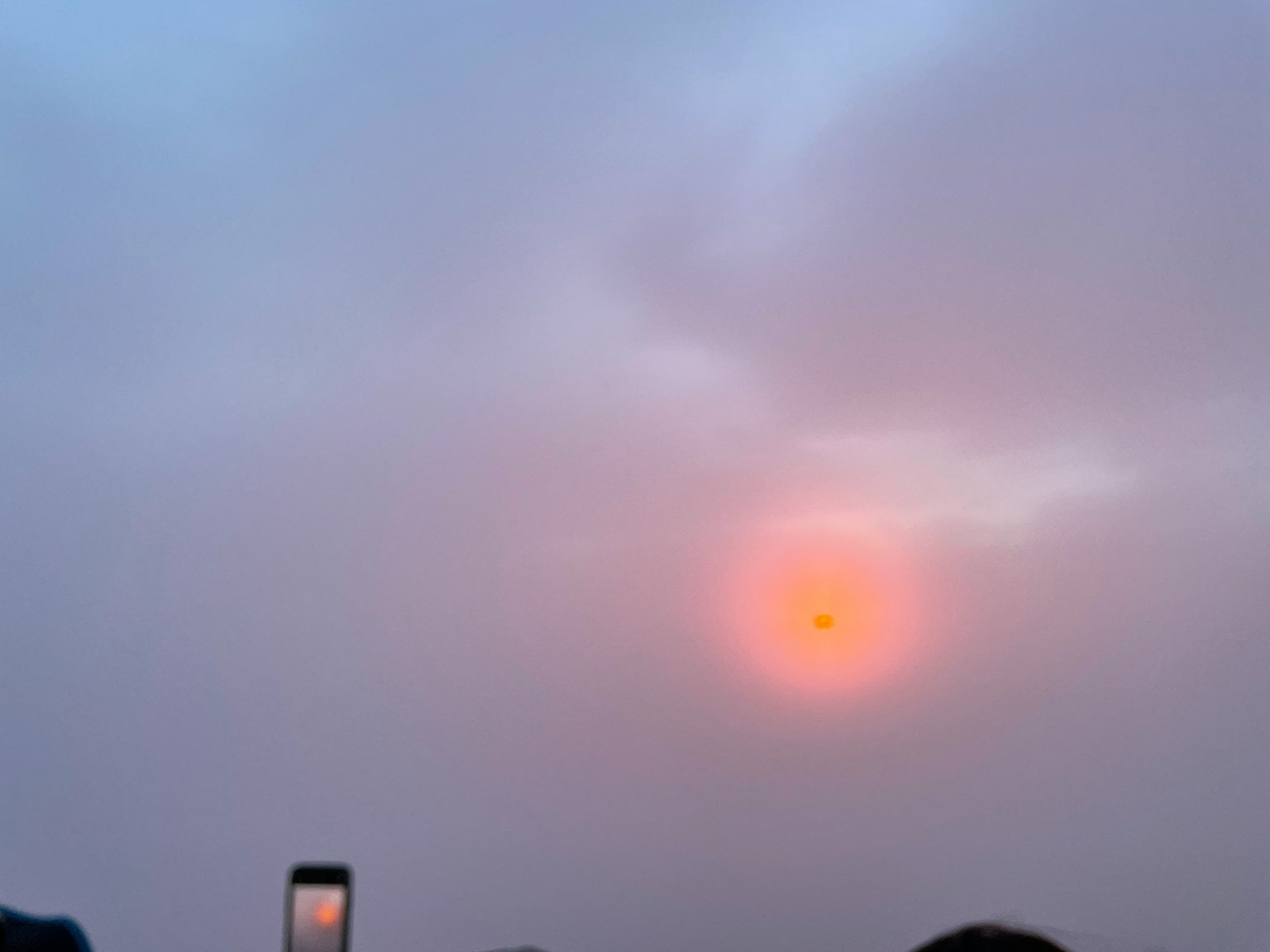 Sole arancione in un cielo nebbioso con nuvole morbide