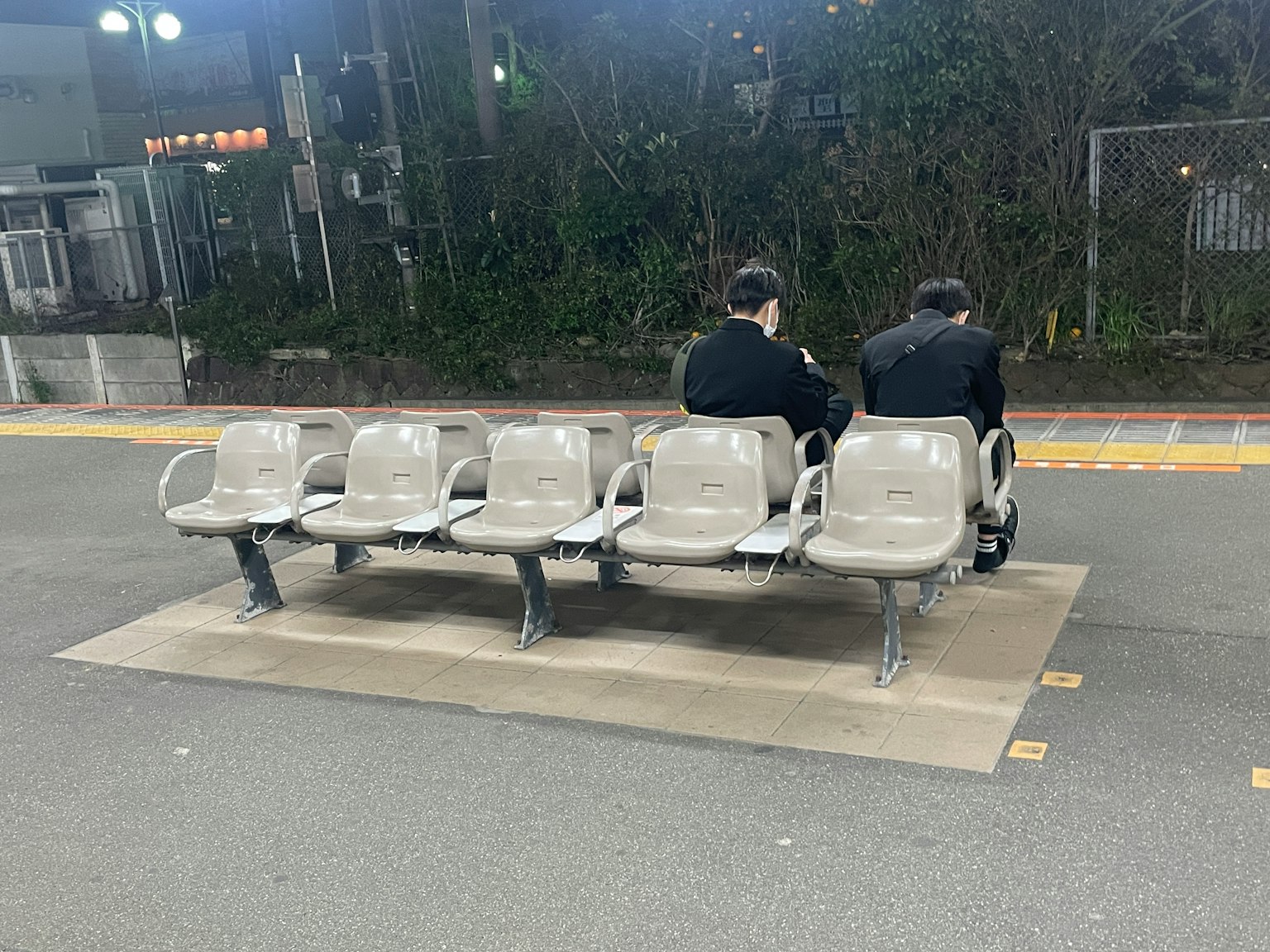 Zwei Männer sitzen auf einer Bank an einem Bahnhof