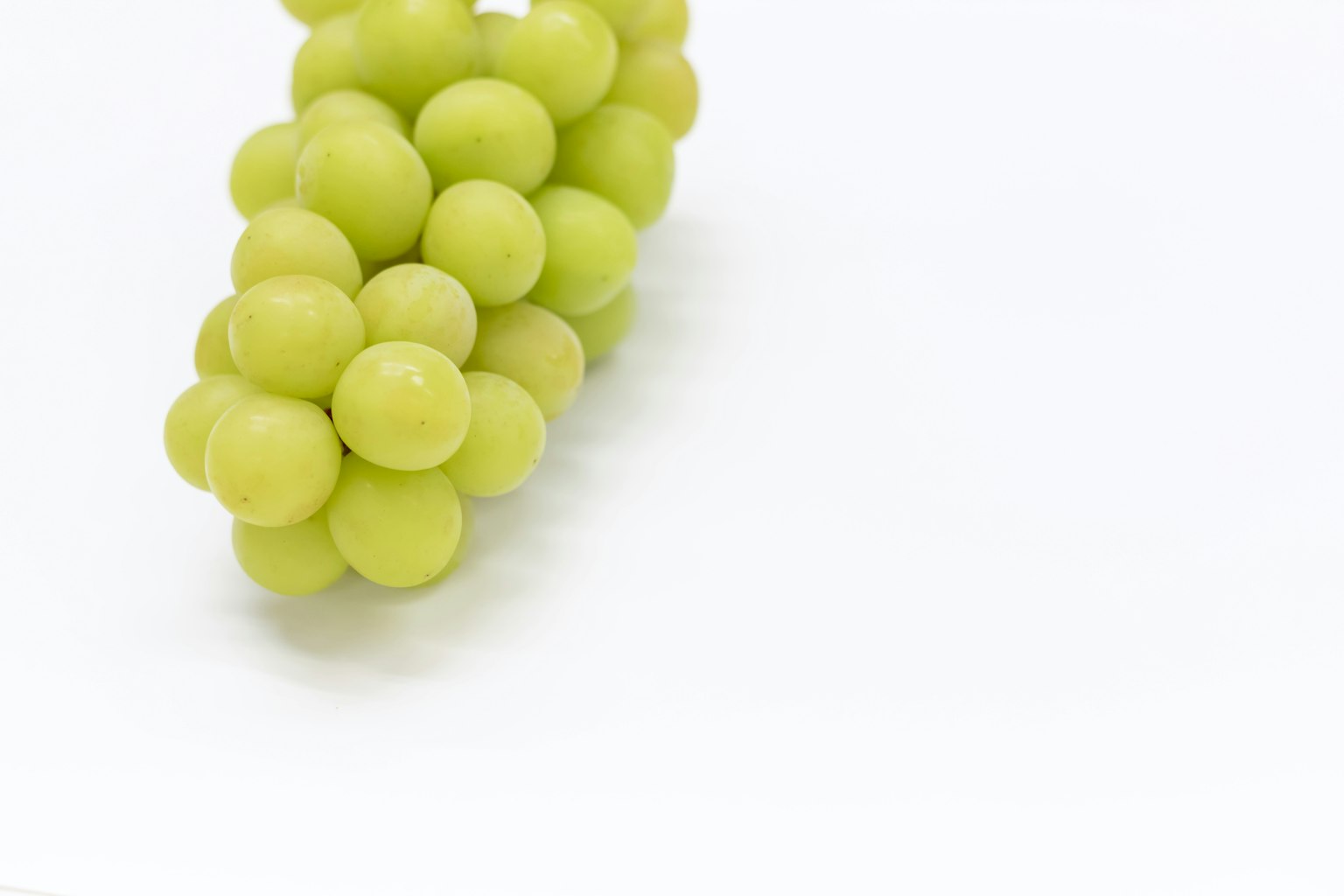 Un racimo de uvas verdes sobre un fondo blanco