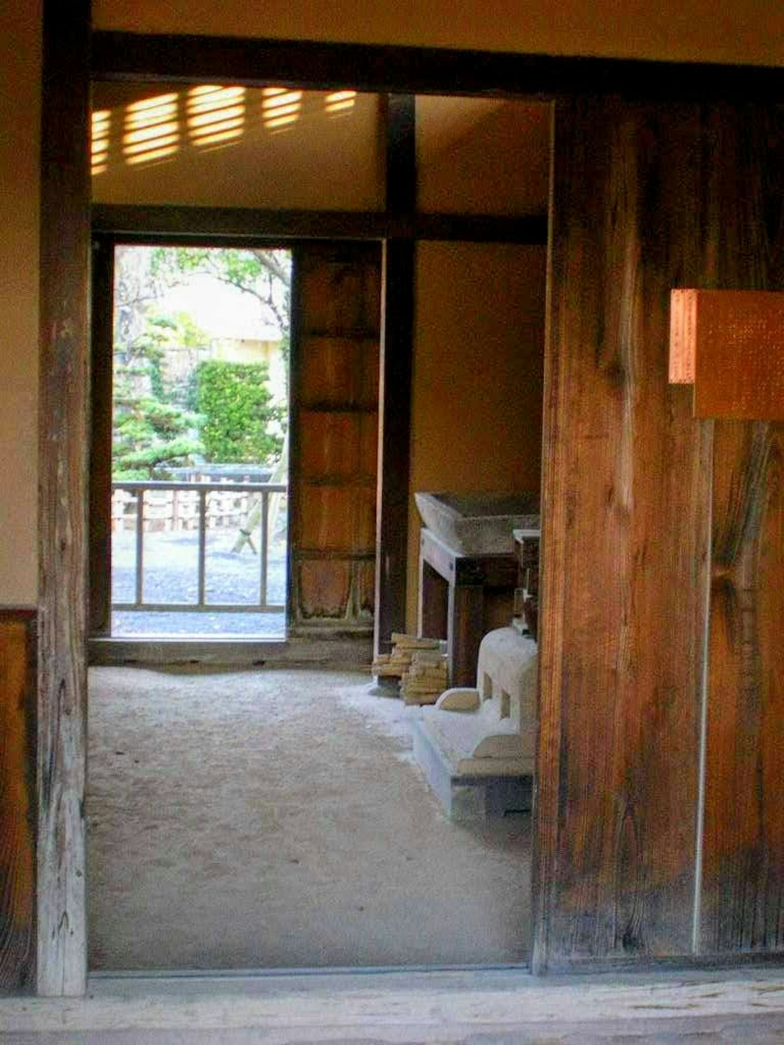 Vista a través de una puerta de madera que muestra un interior japonés tradicional y un jardín