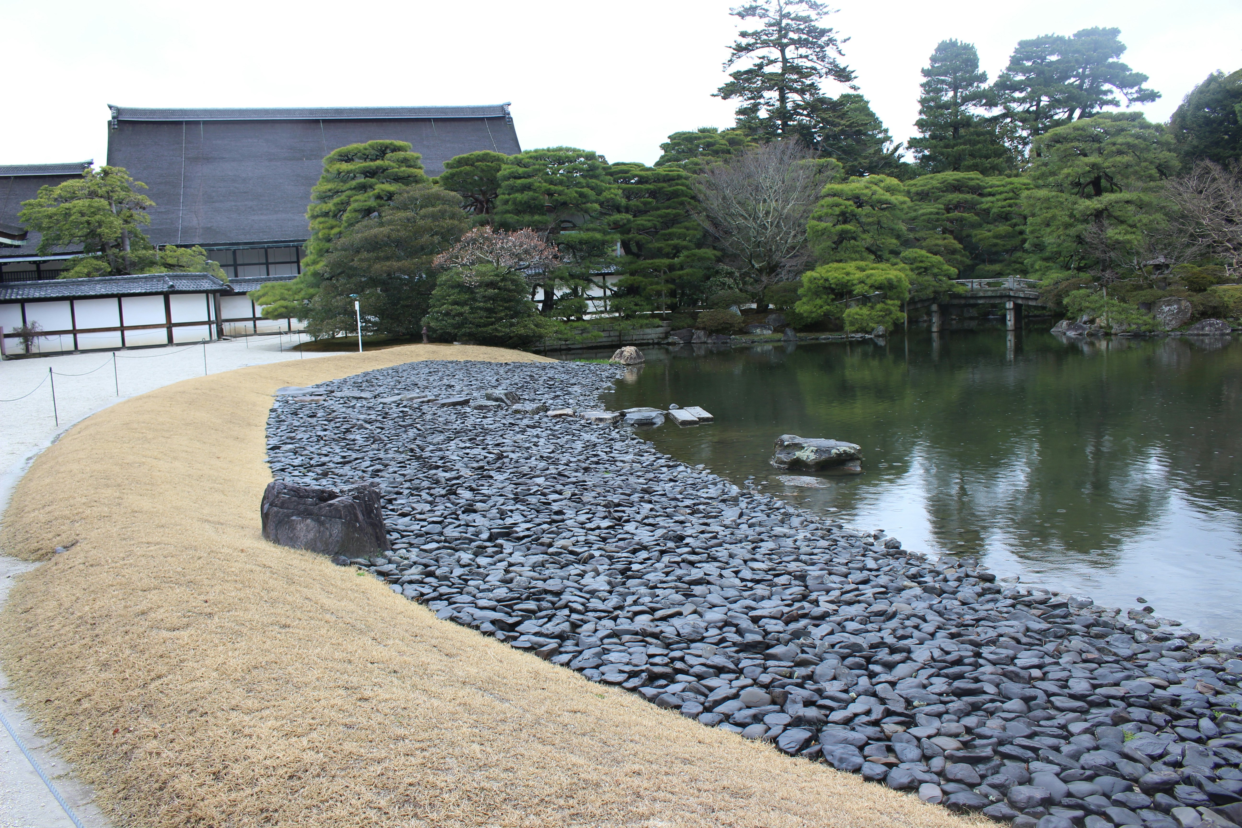 japanischer Garten mit Teich, steinbegrenztem Weg und gepflegten Hecken