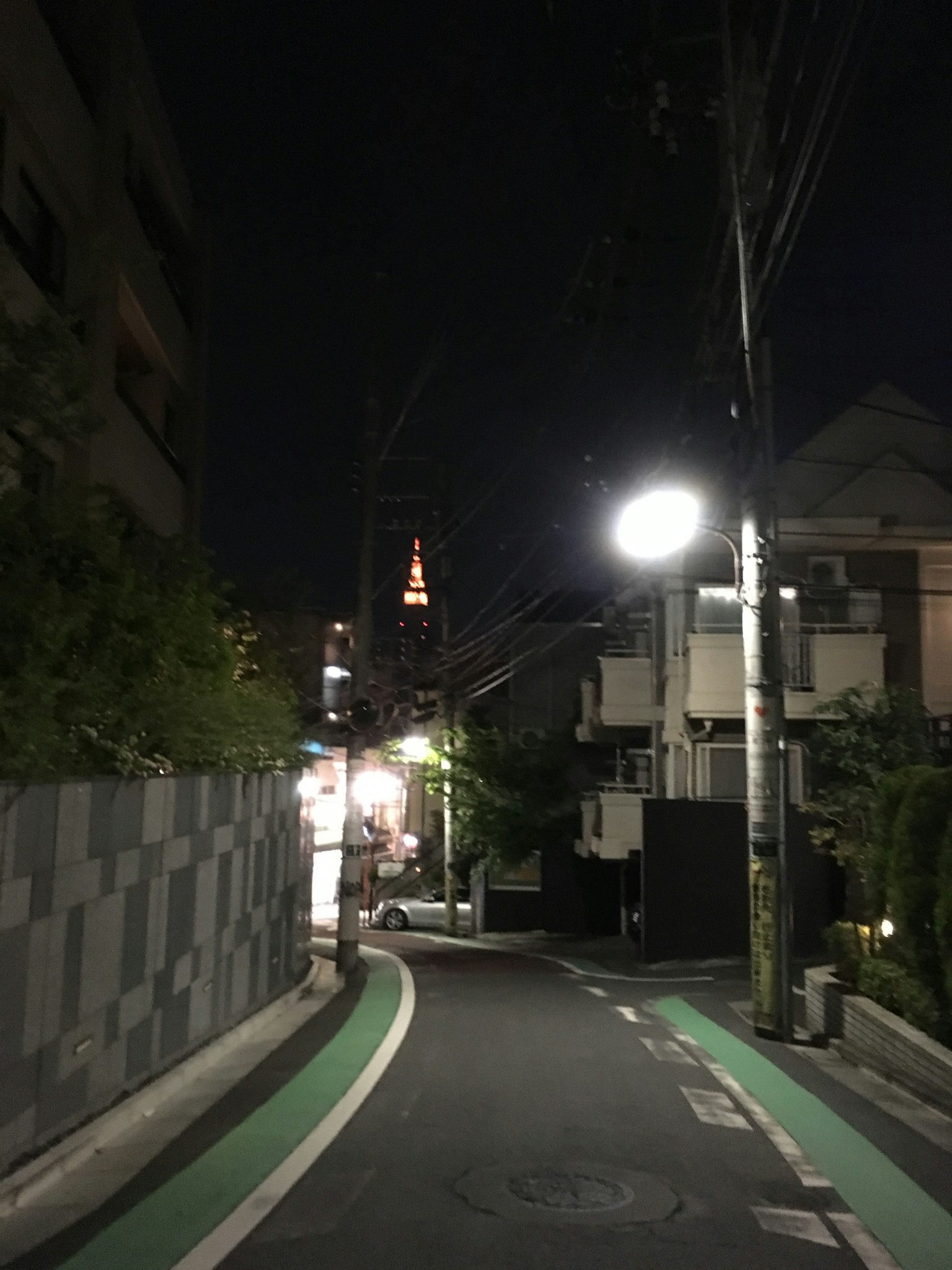 Pemandangan jalan malam dengan Menara Tokyo yang diterangi di kejauhan