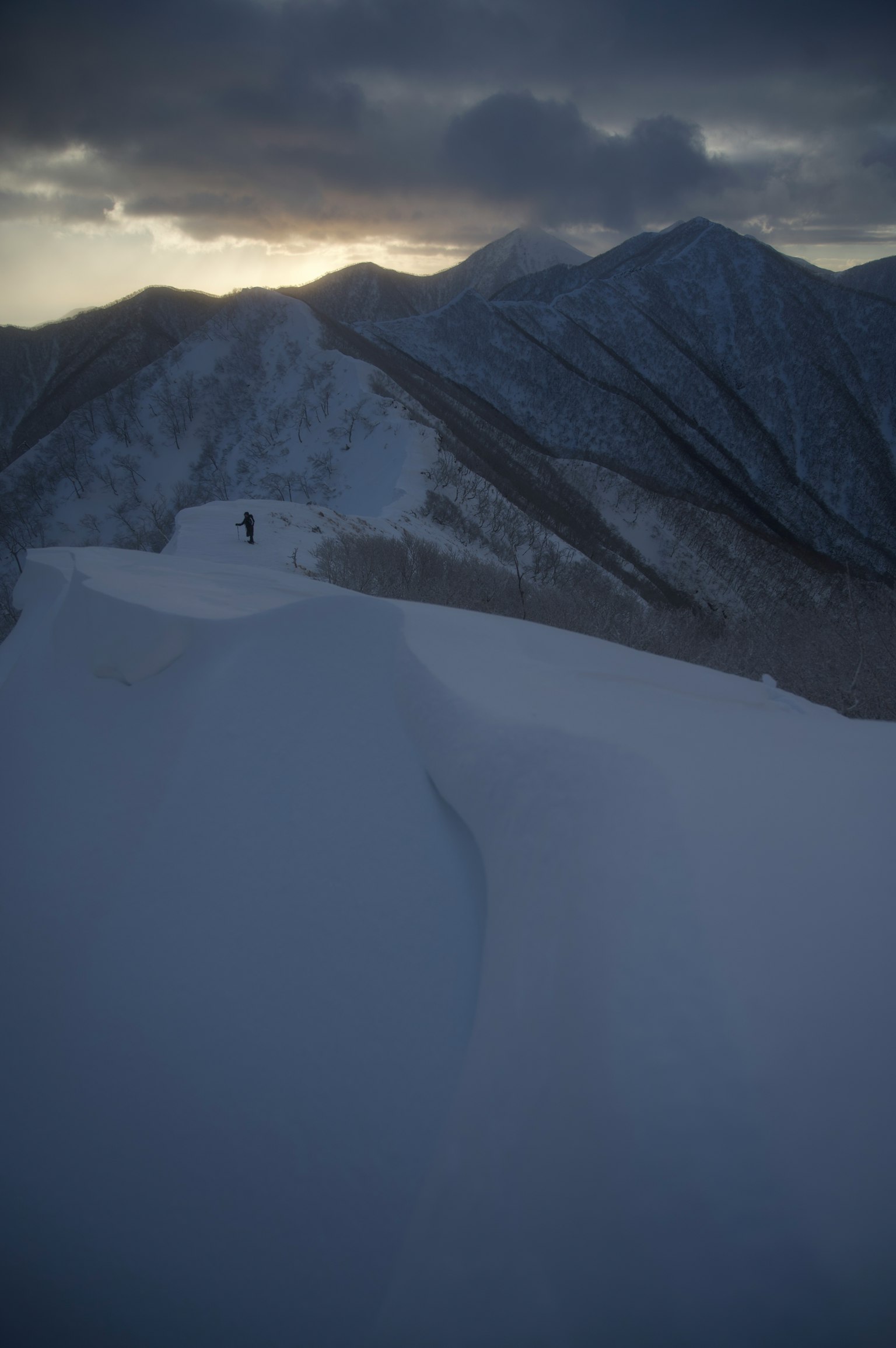 在陰暗天空下雪覆蓋的山脈上的孤獨身影