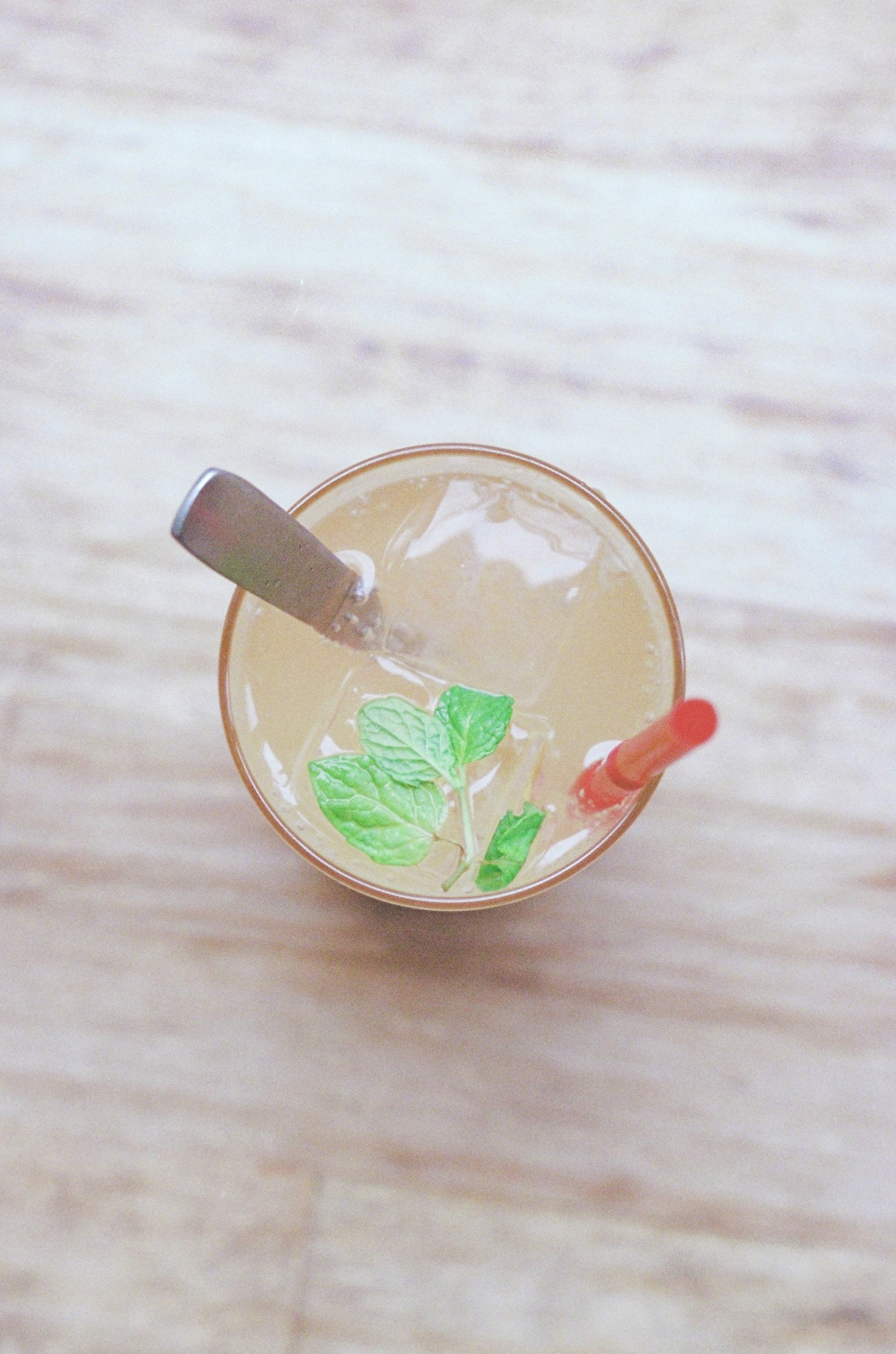 Top view of a drink with ice featuring a spoon and a straw
