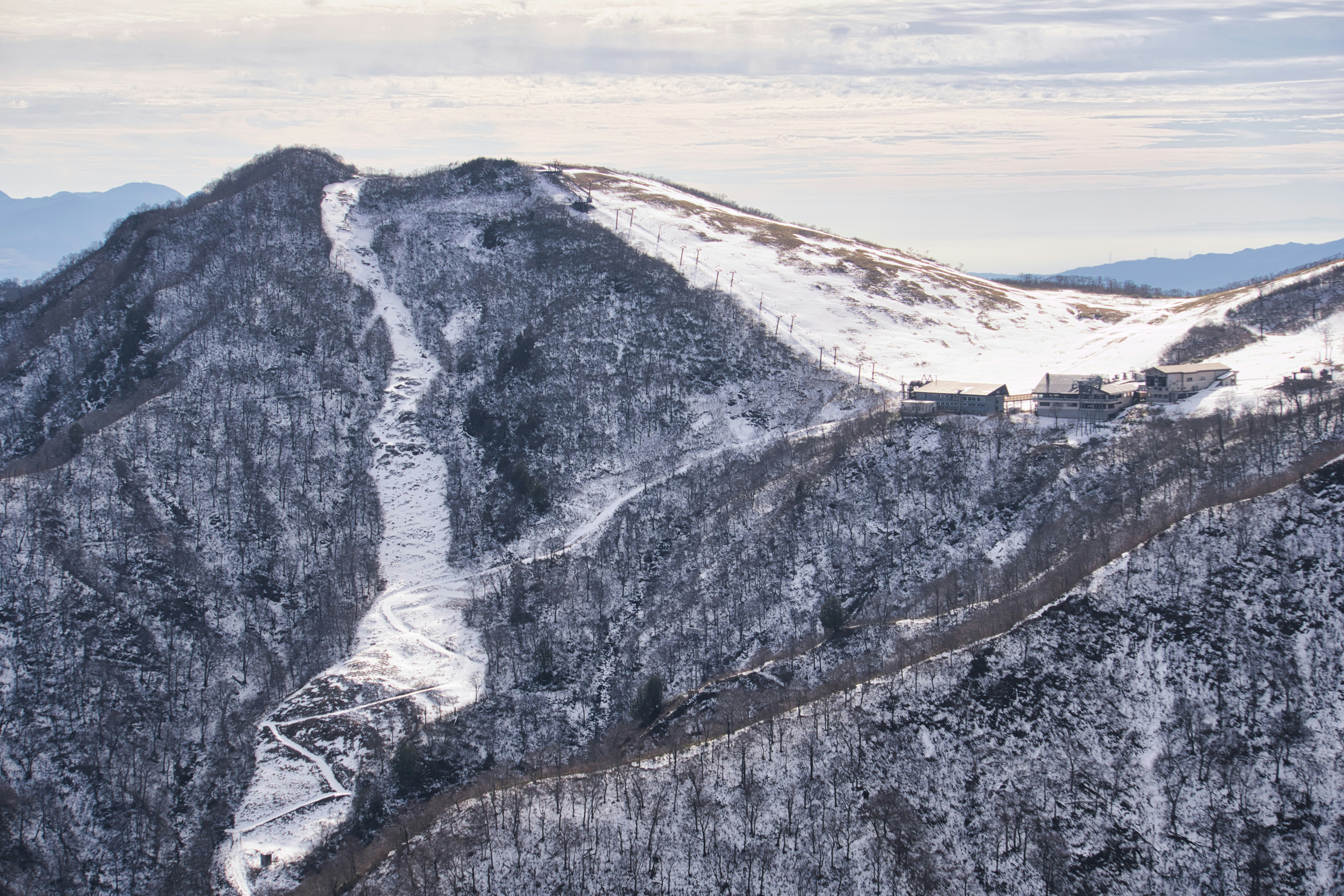 雪の残る山の稜線とトンネルのある峠道