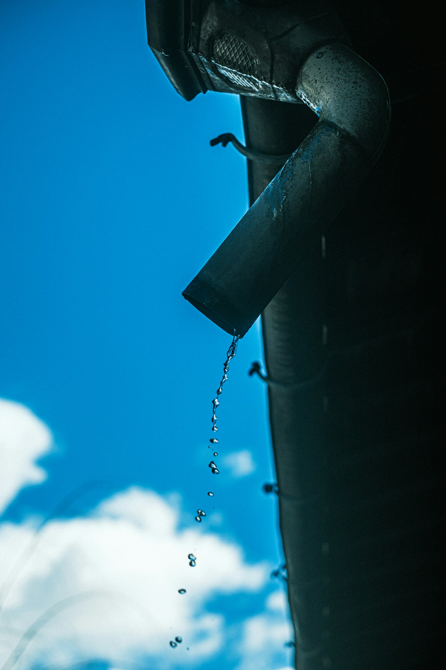 雨水從排水管流出，背景是藍天