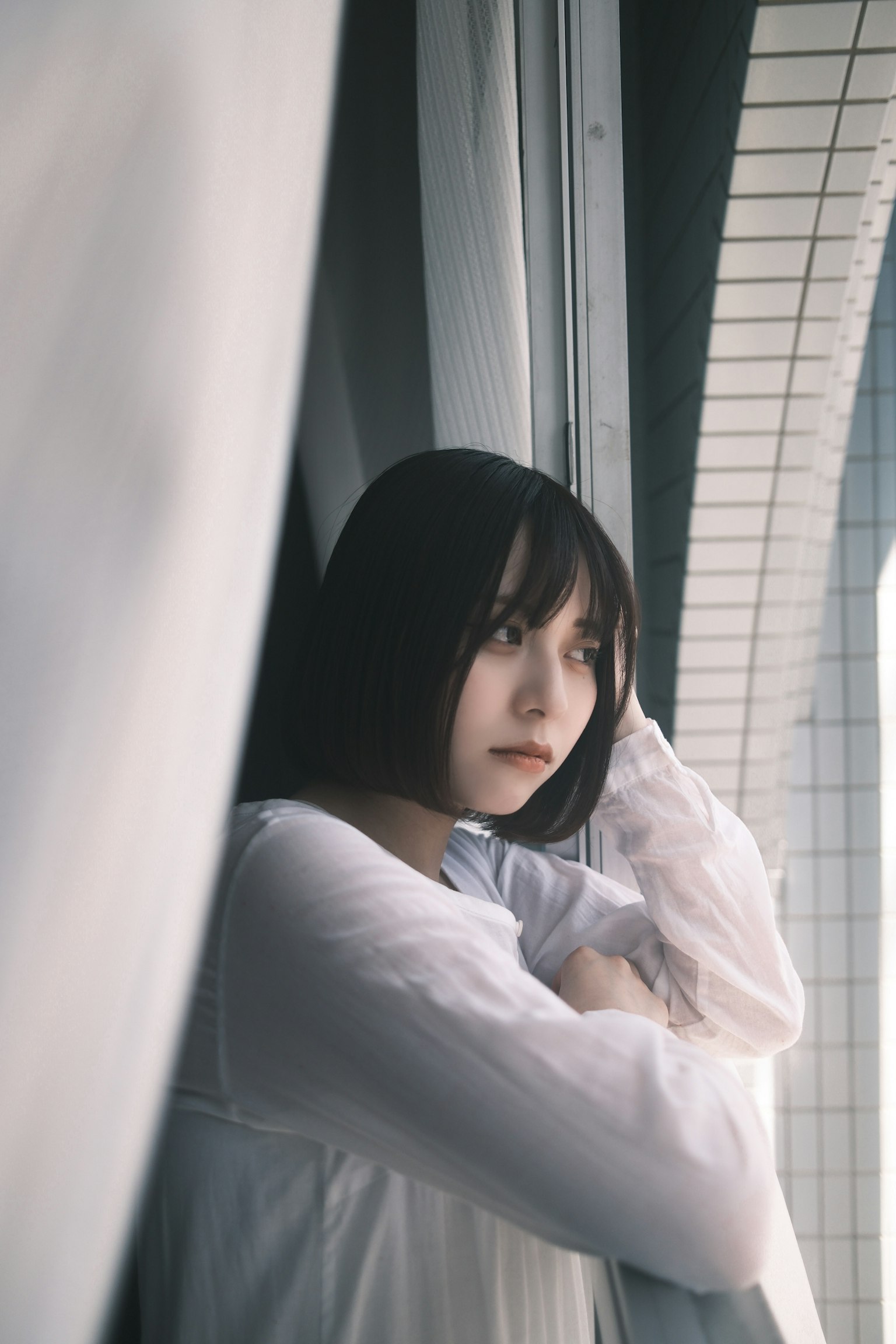窓のそばに立つ女性が白い服を着ている