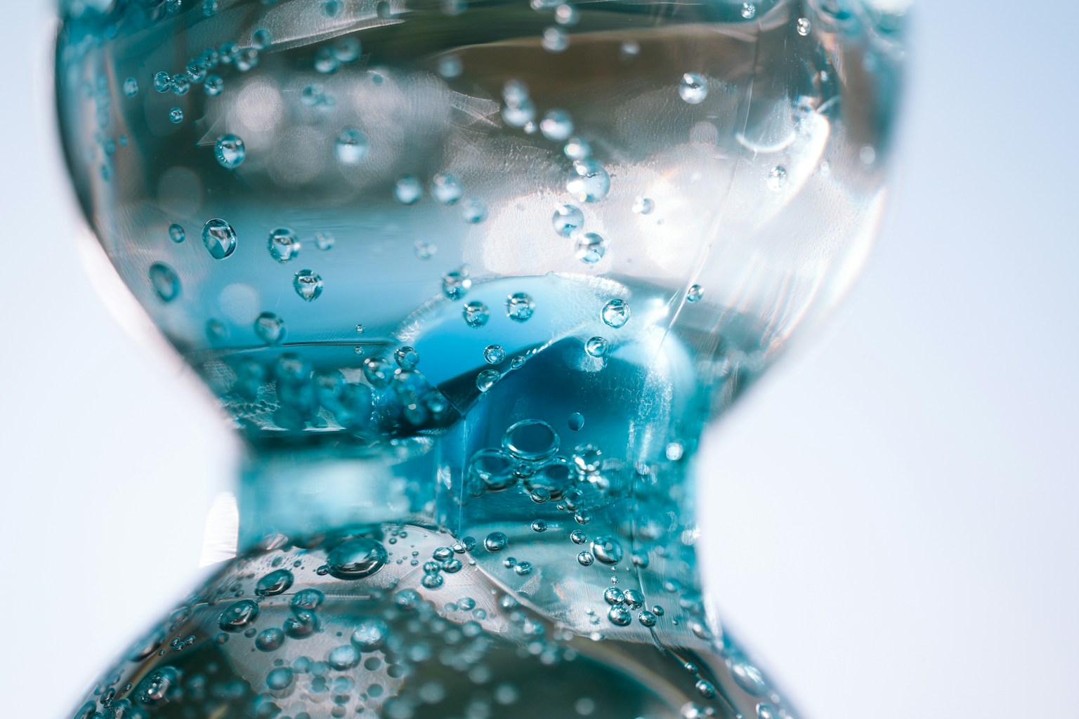 Botol transparan penuh air biru dan gelembung