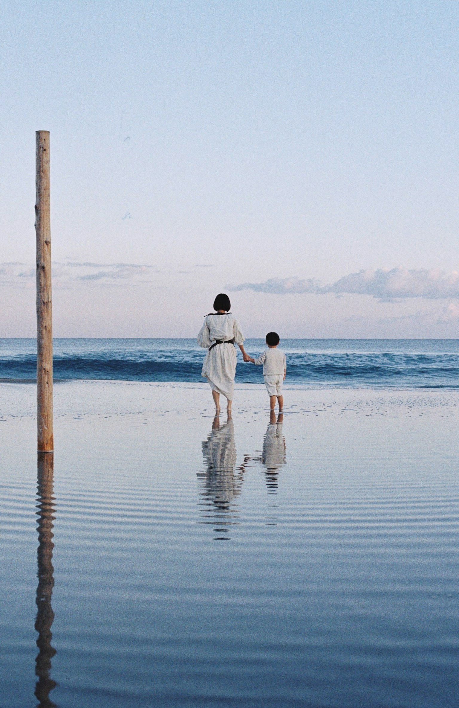 Madre e figlio in piedi sulla spiaggia vicino all'acqua
