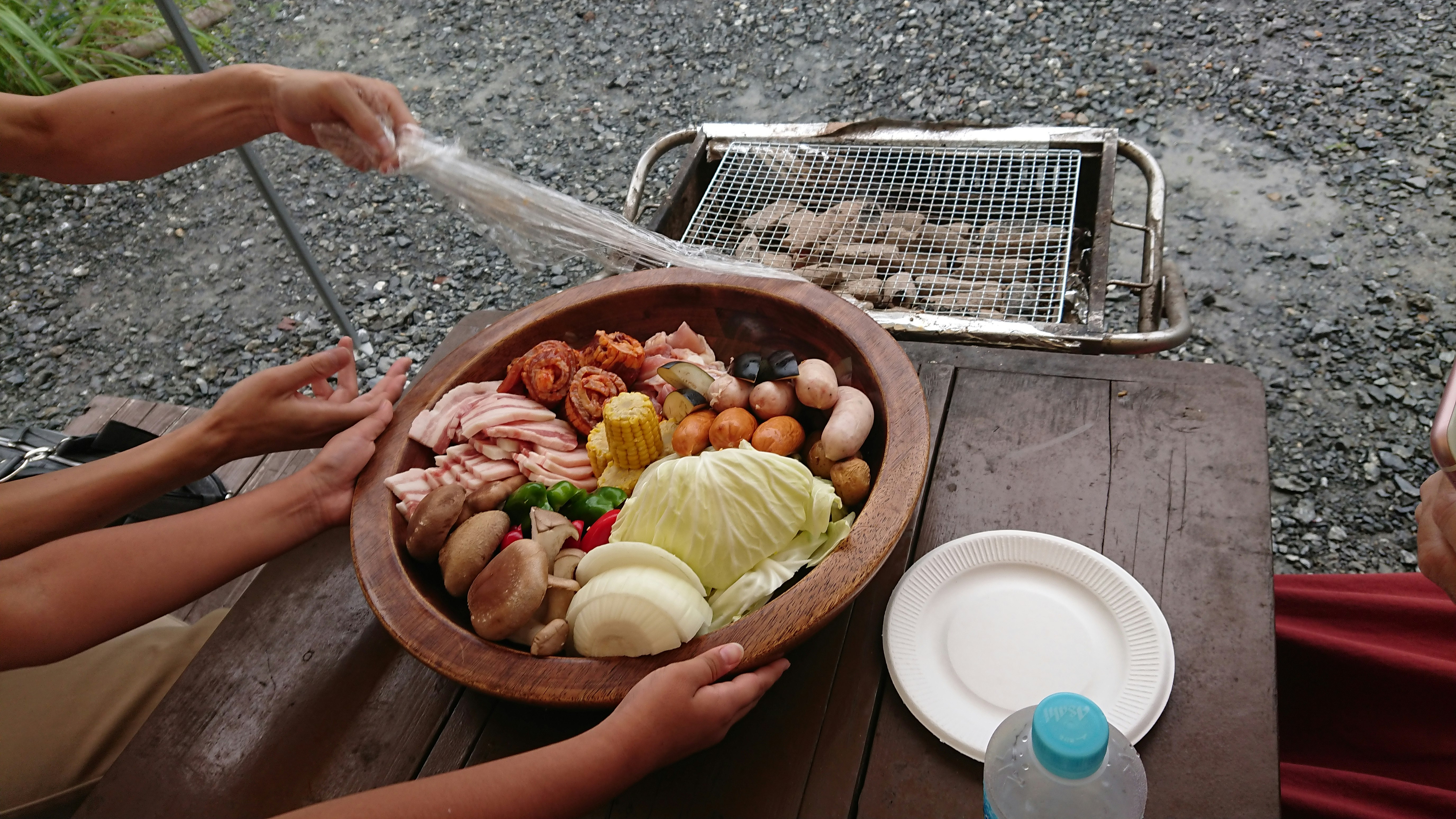 Un gran tazón de ingredientes para asar con una parrilla al fondo