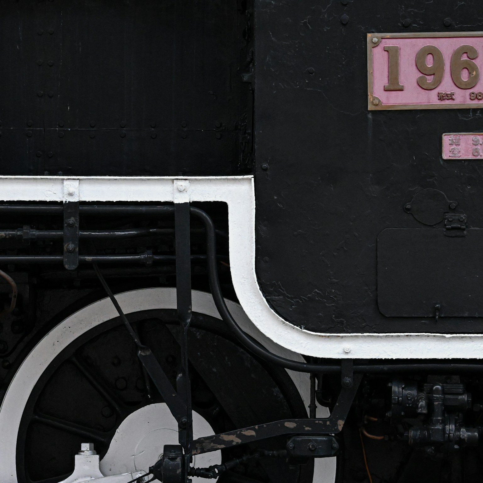 มุมมองด้านข้างของรถจักรไอน้ำสีดำที่มีหมายเลข 196 และท่อสีขาว