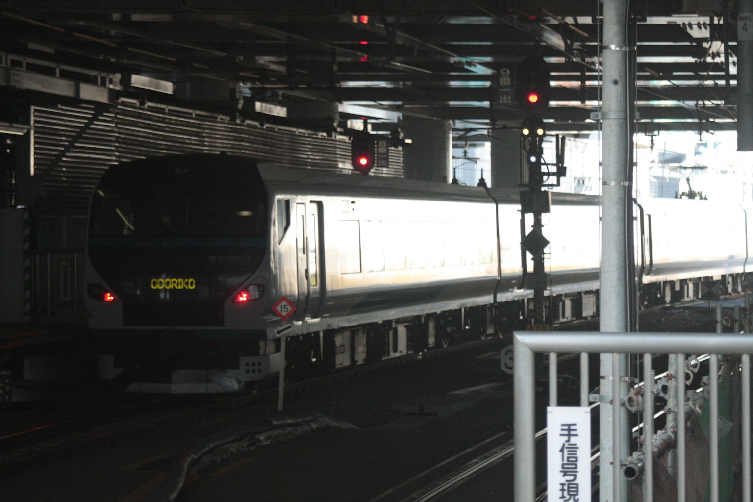 Train arrivant à une station faiblement éclairée avec des signaux lumineux