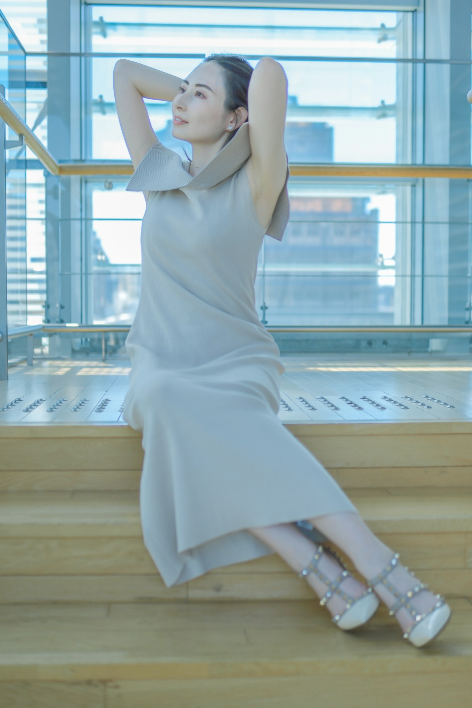 A woman in a soft fabric dress relaxing on a wooden staircase