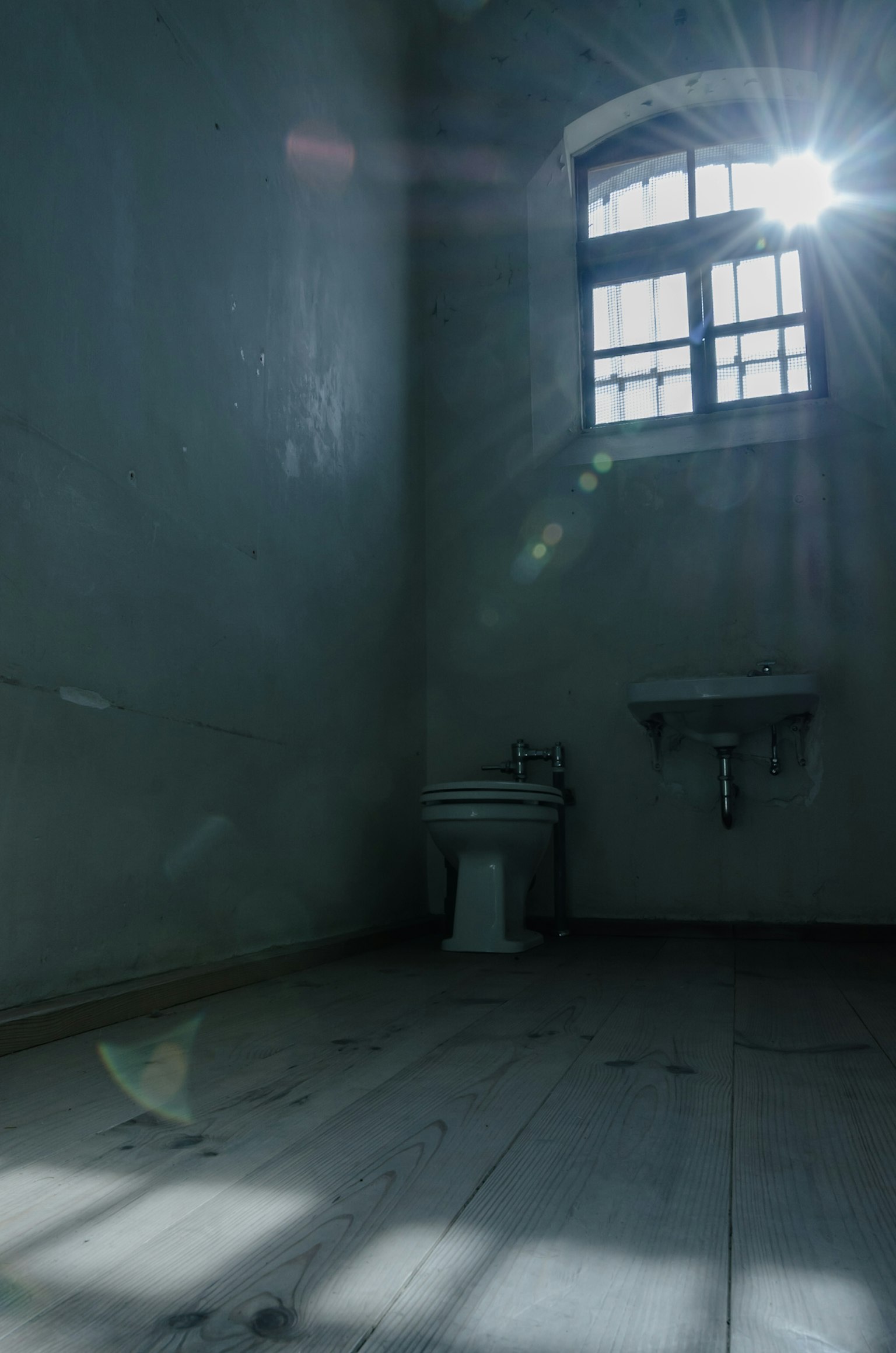 Căn phòng tối với bồn cầu và ánh sáng mặt trời chiếu qua cửa sổ