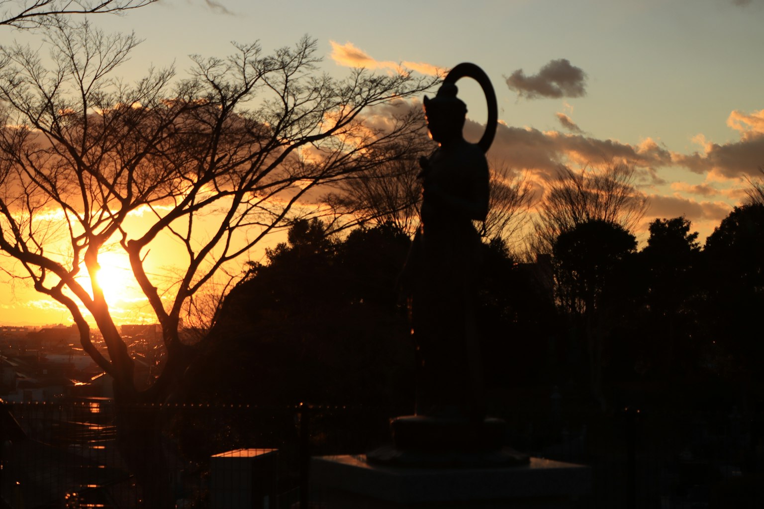 Silhouette of a goddess statue against a sunset