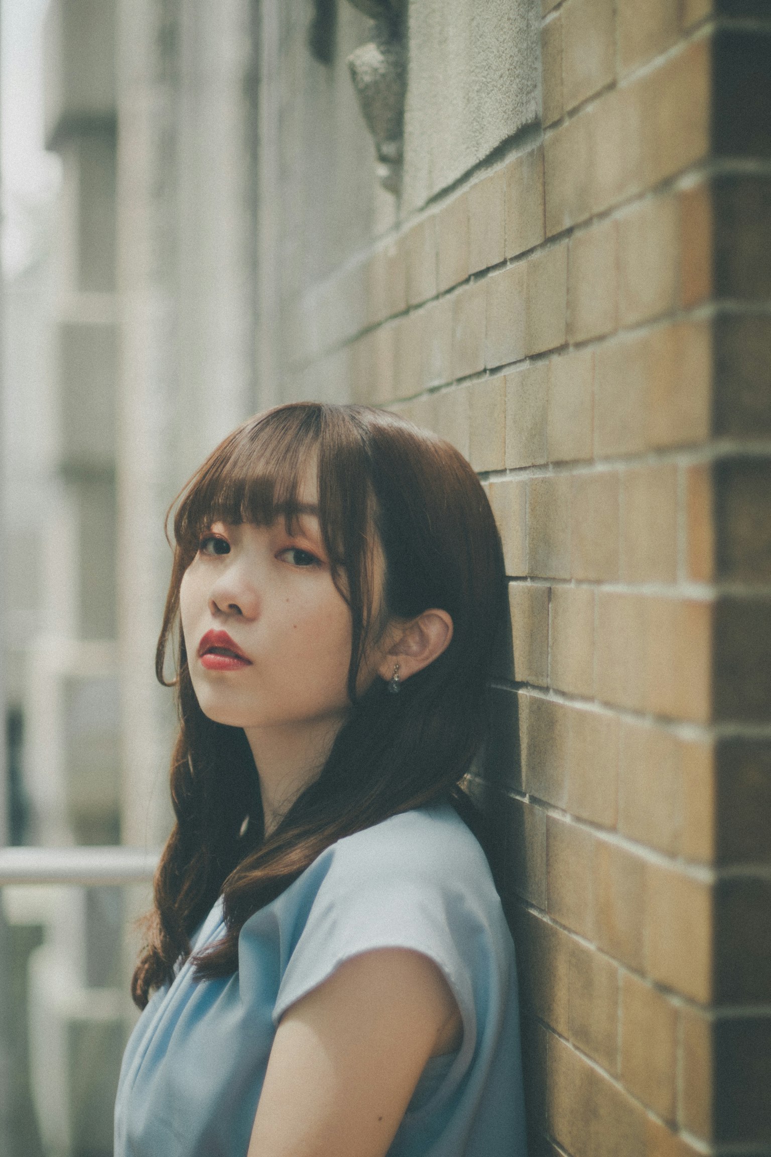 靠在墙上的女性肖像，棕色头发和柔和的表情