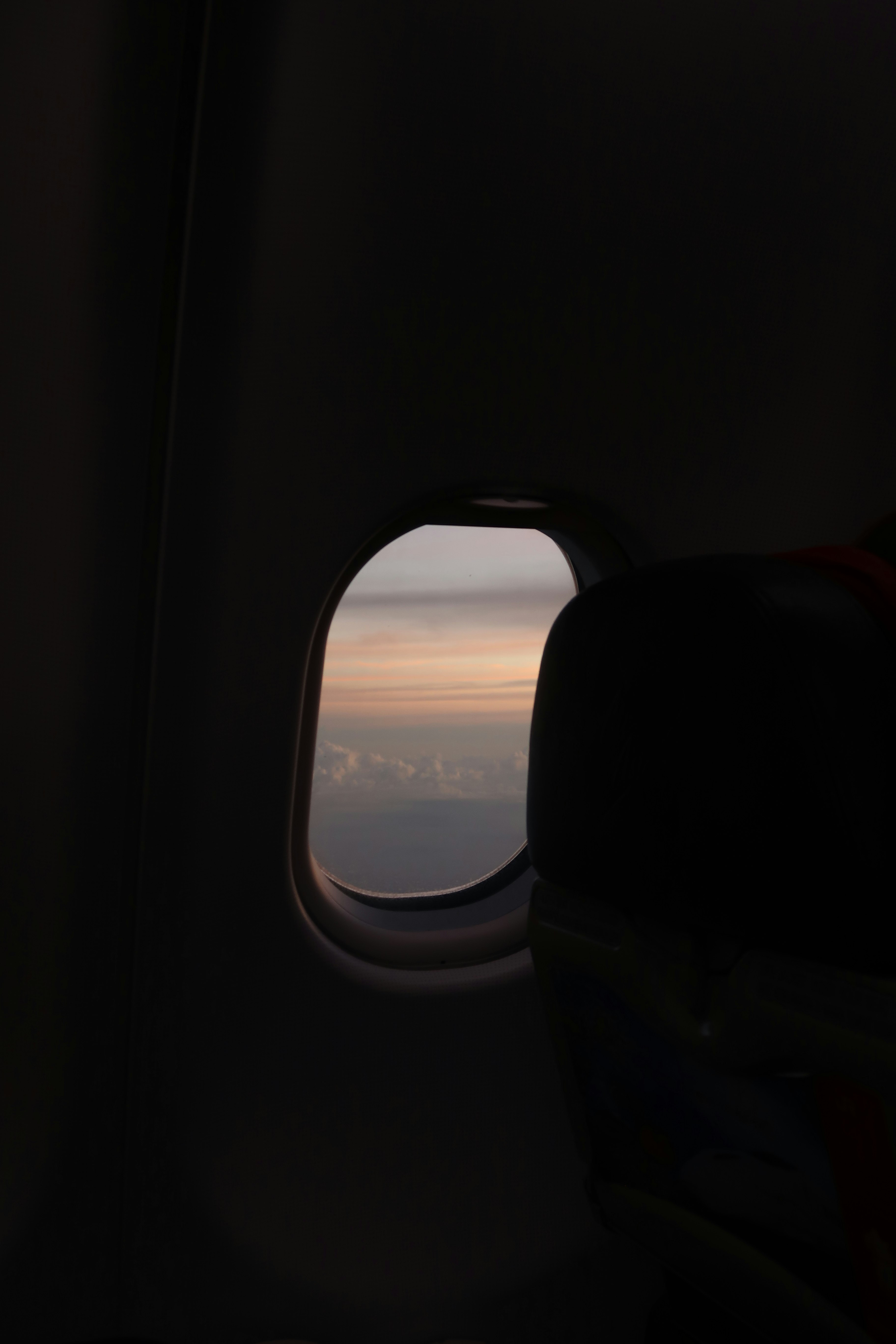 飛行機の窓から見える夕焼けの空と雲