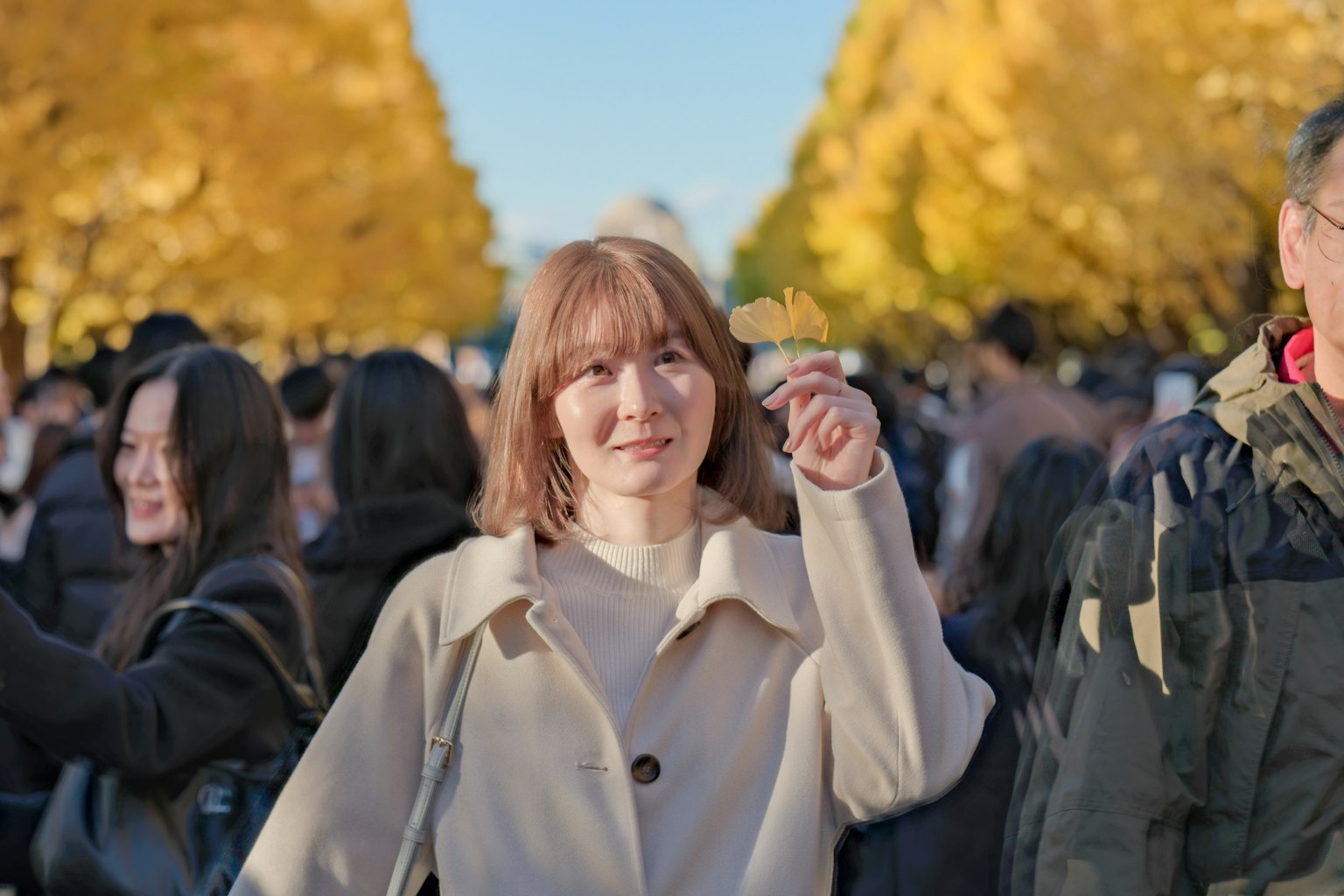 秋天的公园里微笑的女性，周围有许多人