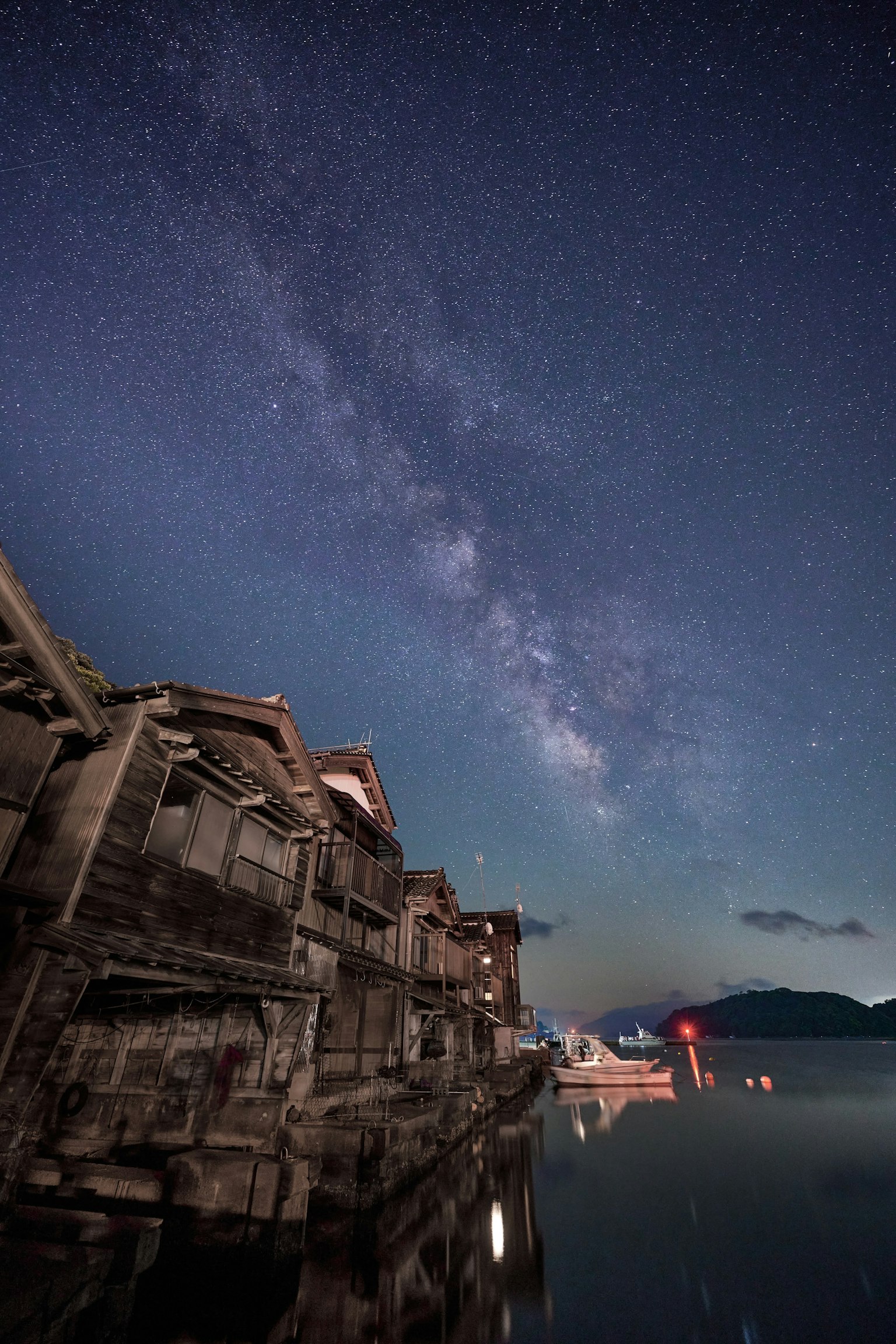 Silhouette of old buildings reflected in calm water under a starry sky