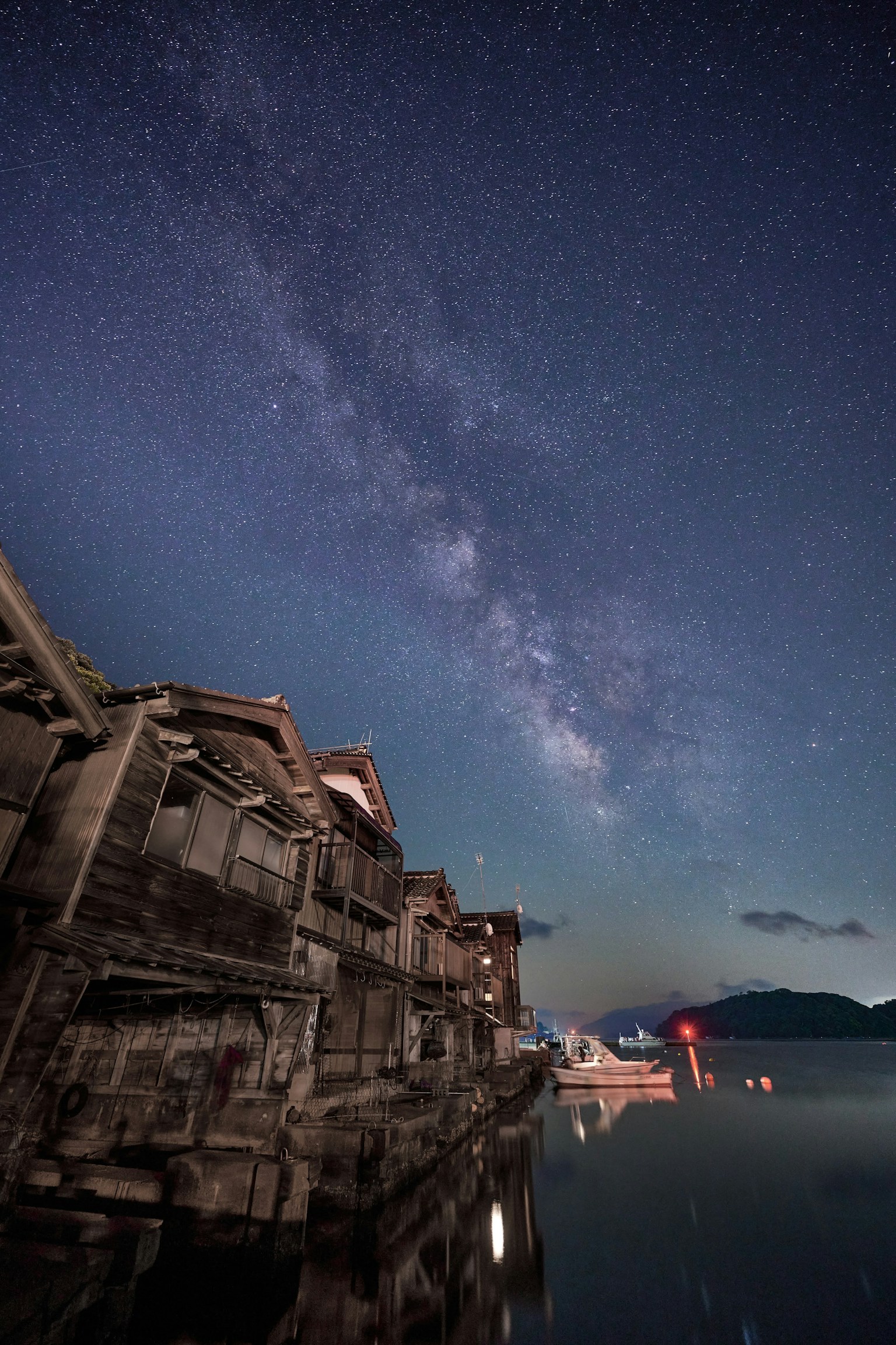 Silueta de edificios antiguos reflejados en agua tranquila bajo un cielo estrellado
