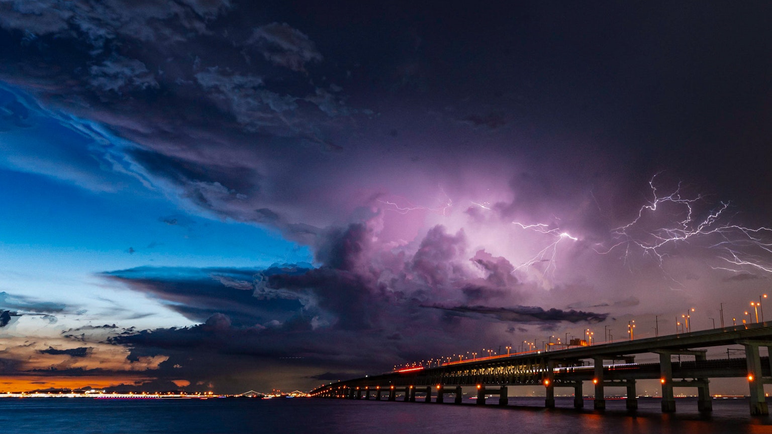 Cielo notturno drammatico con fulmini e nuvole scure sopra un ponte