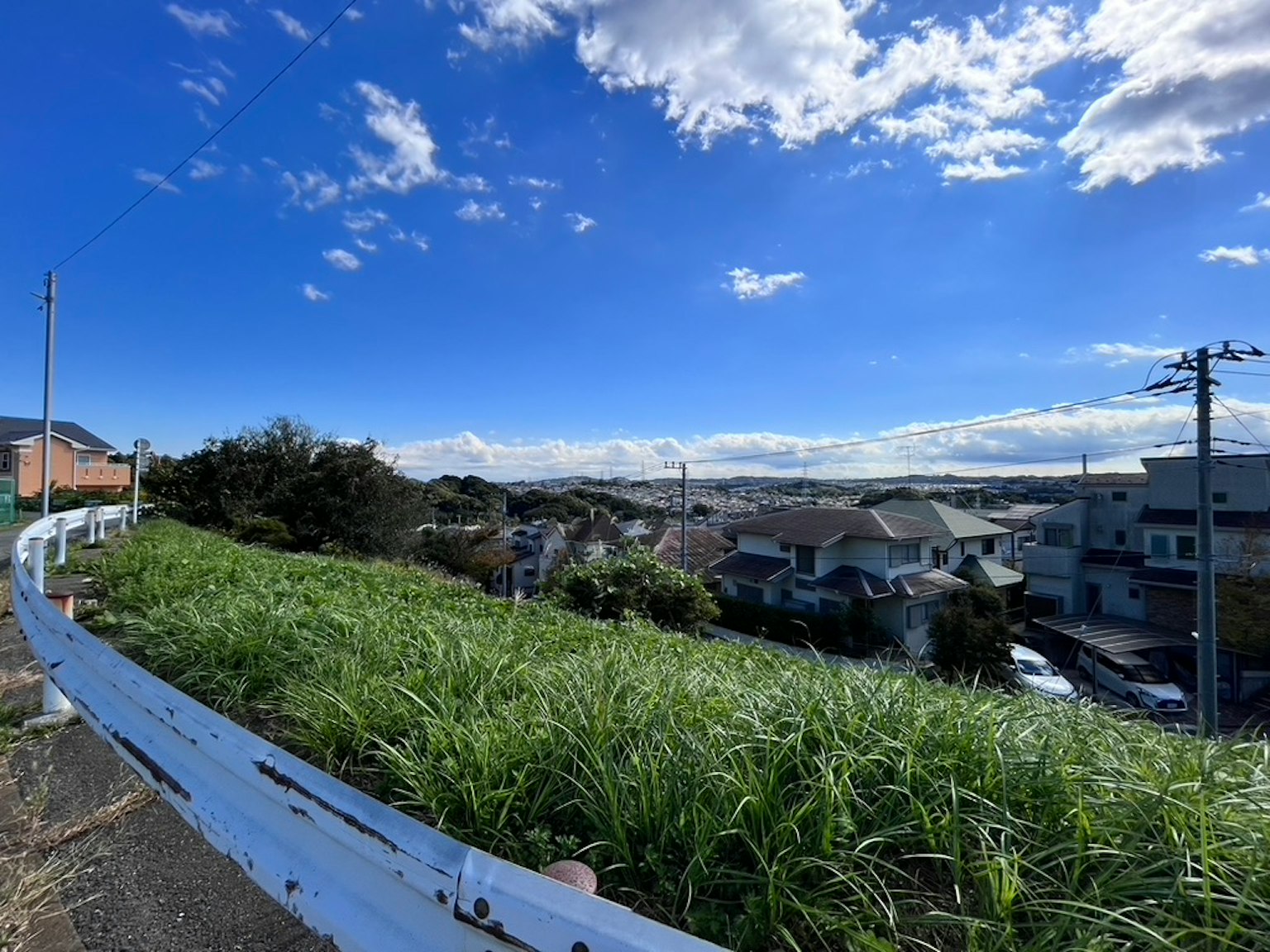 Landscape with blue sky and white clouds featuring houses and grassy hills
