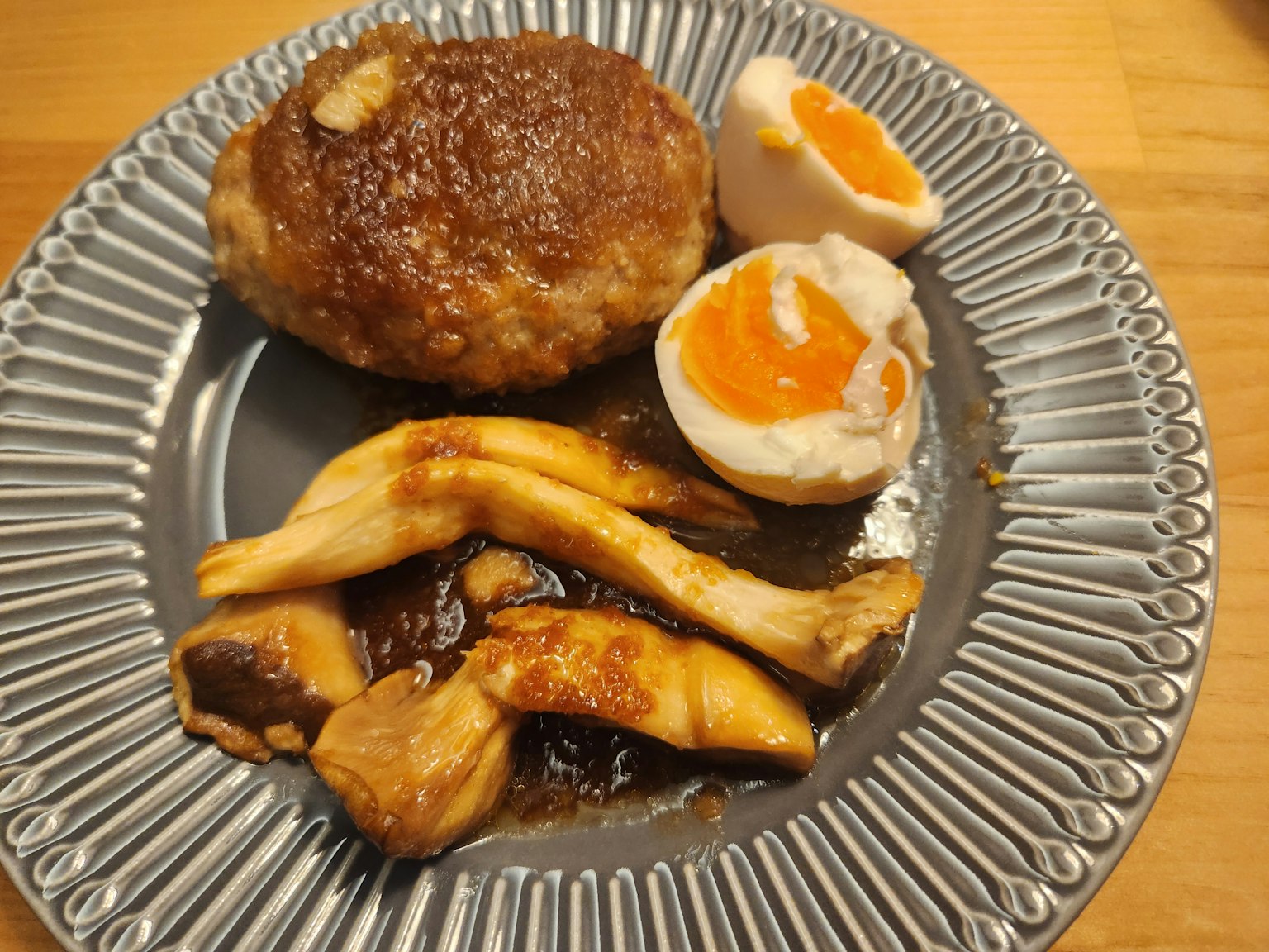 Piring dengan hamburger, telur setengah matang, dan jamur tumis