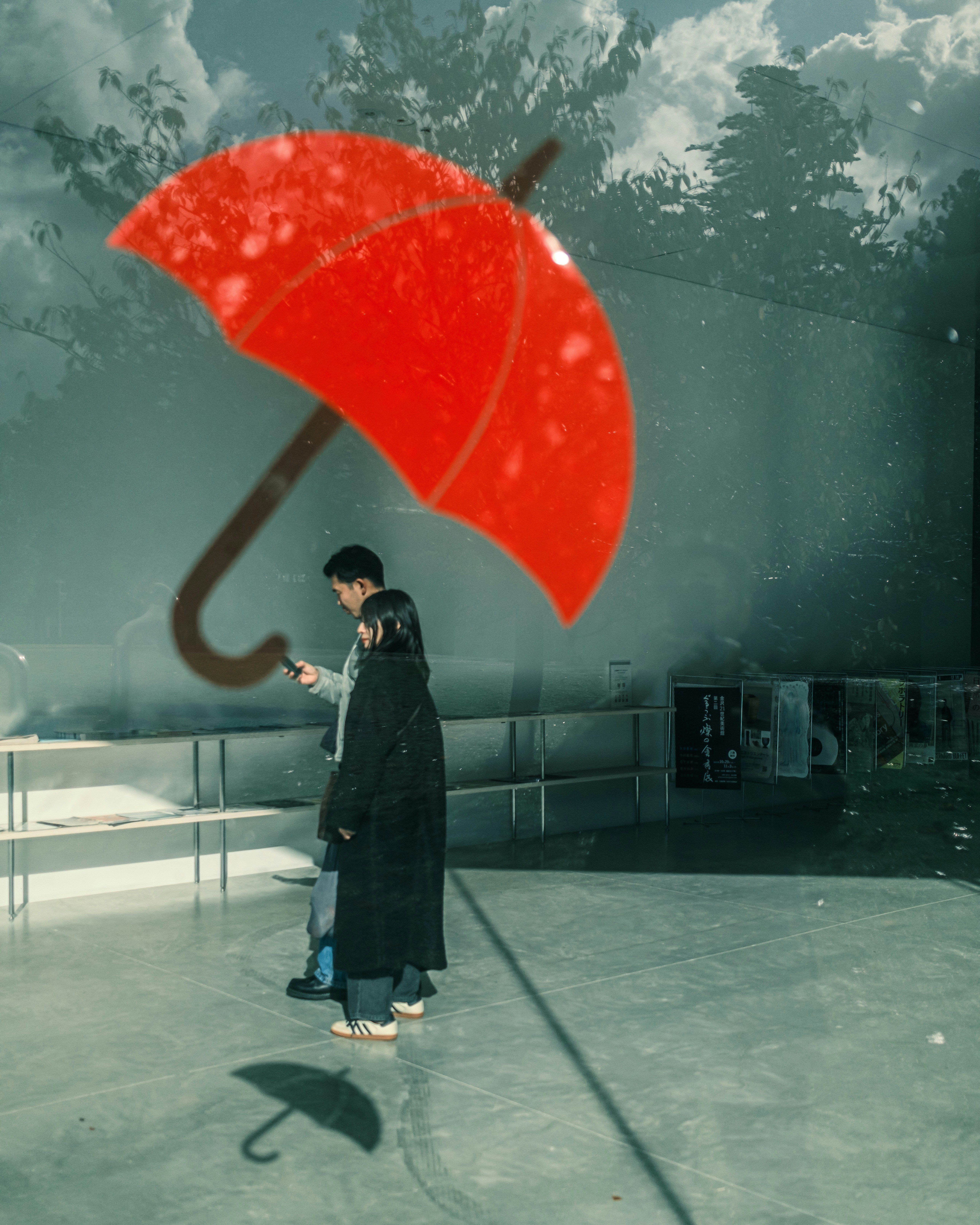 雨の屋外で赤い傘をさす人物のある広場
