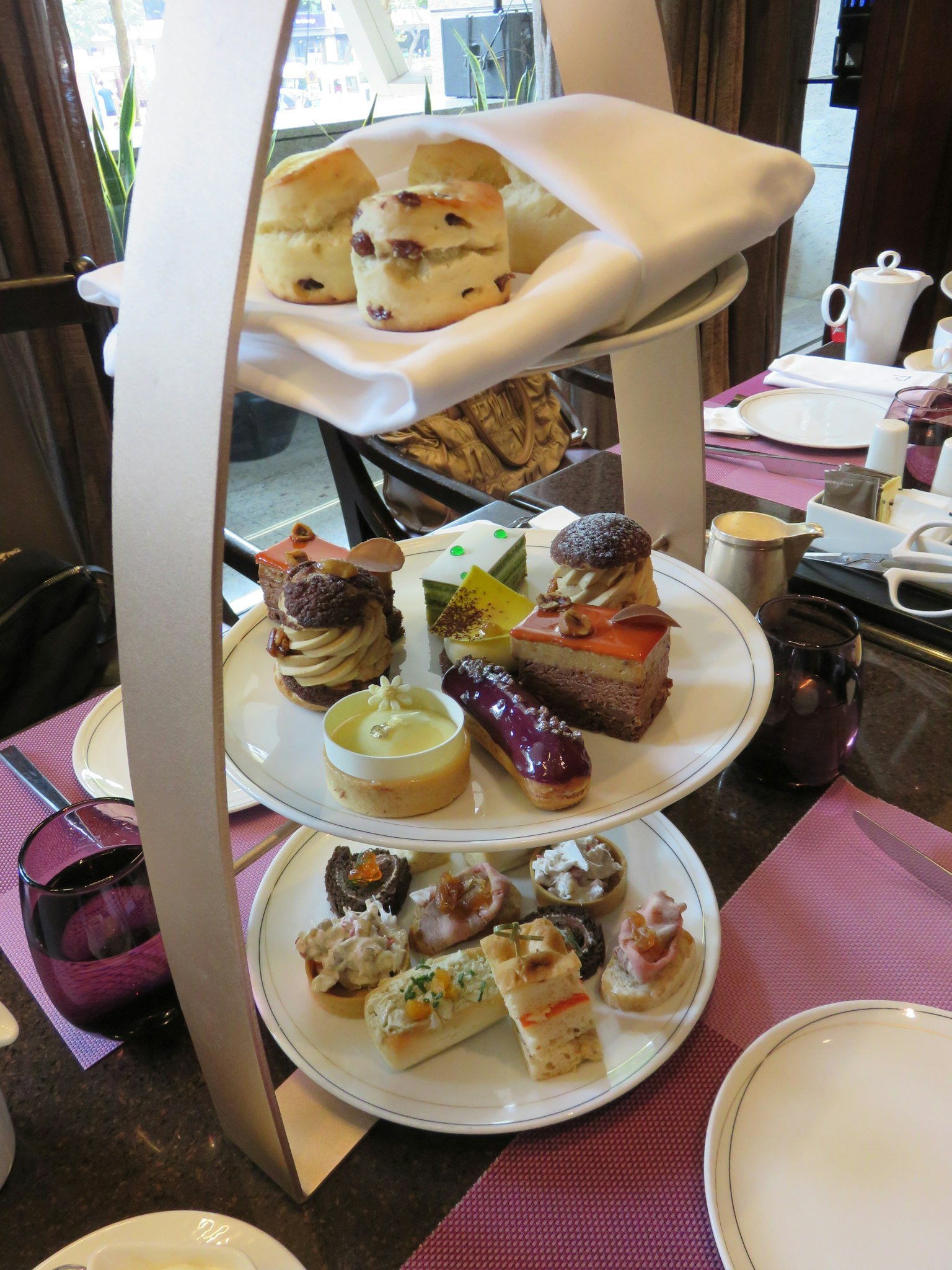 Plato de tres niveles para el té de la tarde con sándwiches y pasteles variados