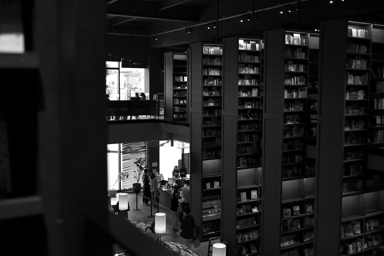 モダンな図書館の内部の黒と白の写真 高い本棚と訪問者がいる