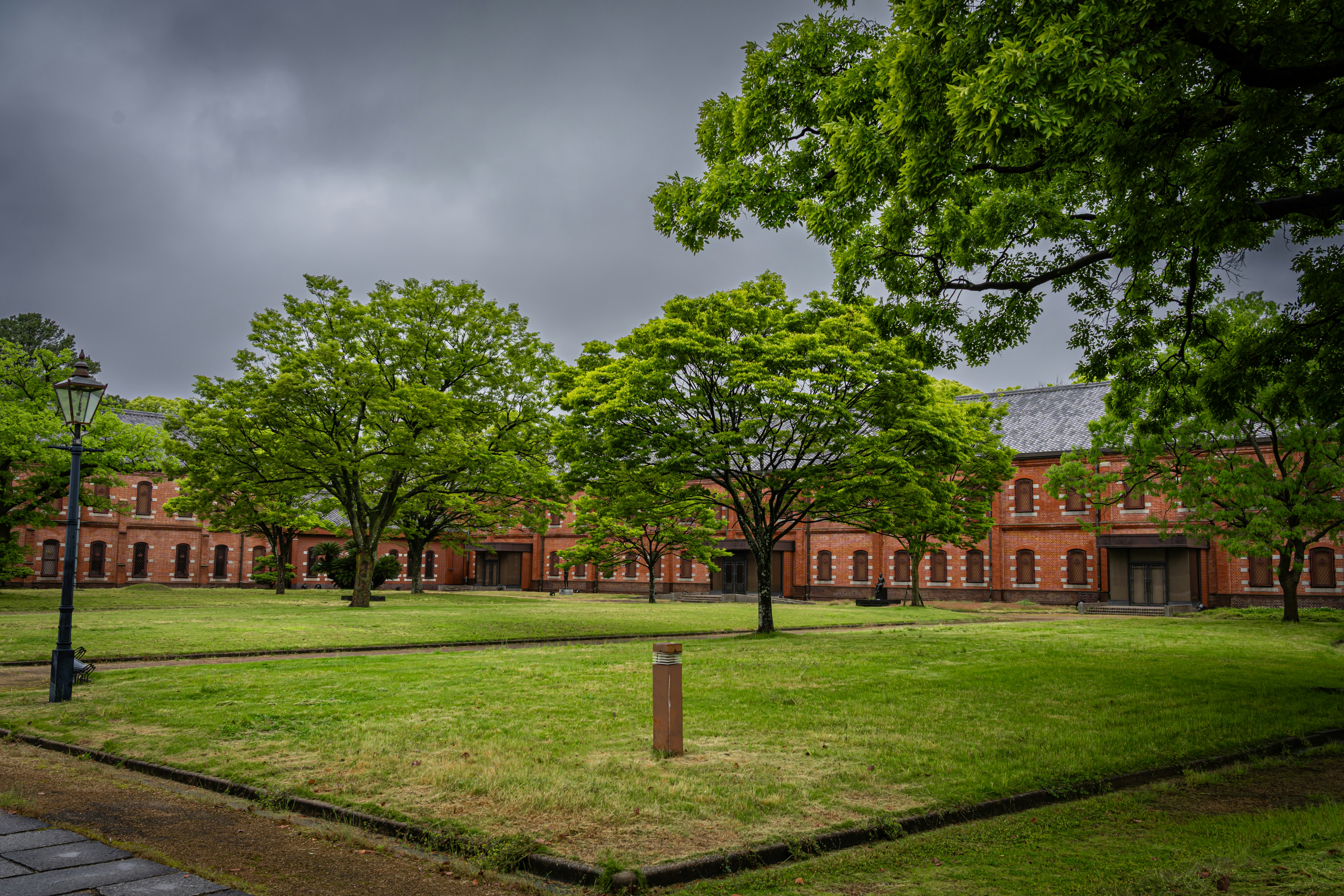 cour d’école avec pelouse verte, arbres et bâtiments en briques