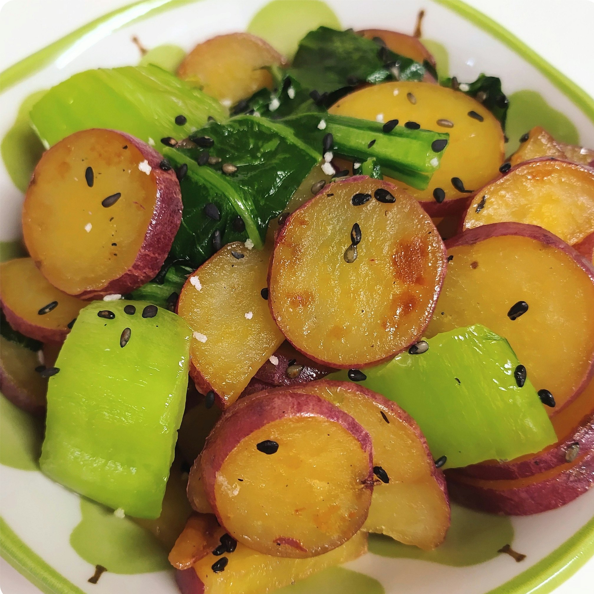 Salade de légumes aux morceaux verts et orangés, parsemée de sésame noir