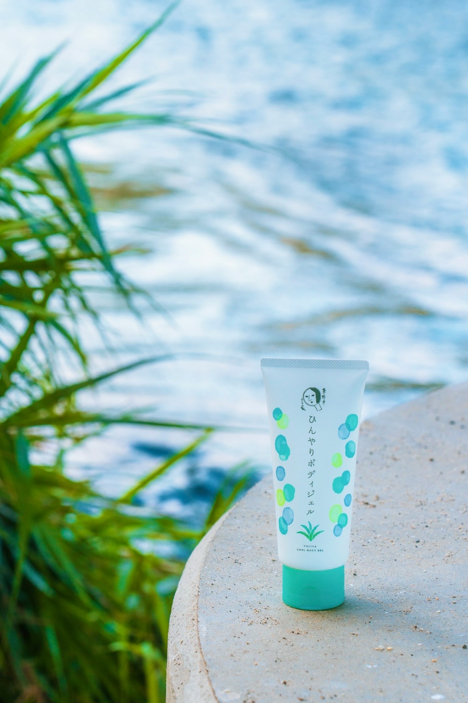 Eine Tube Hautpflegecreme am Wasser mit grünem Gras im Hintergrund