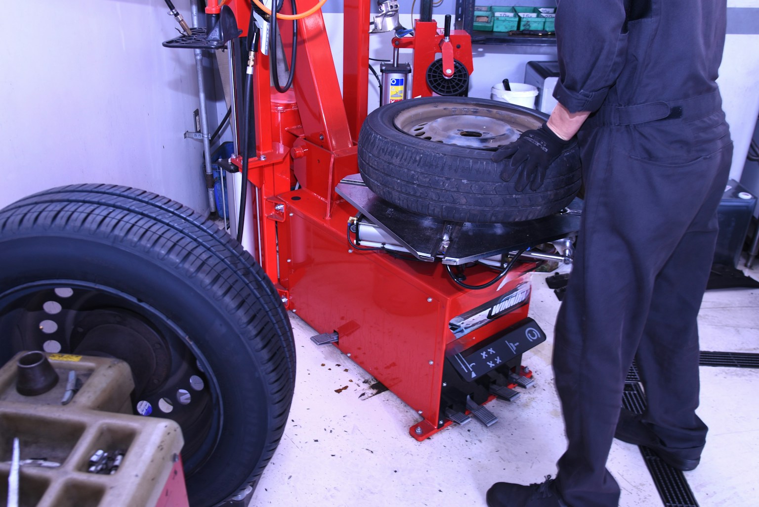 赤いタイヤチェンジャーでタイヤを交換している作業員