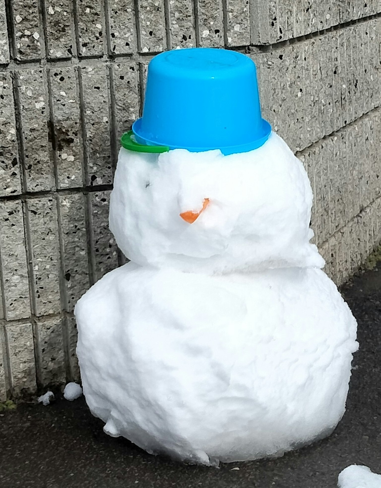Snowman made of snow wearing a blue bucket hat